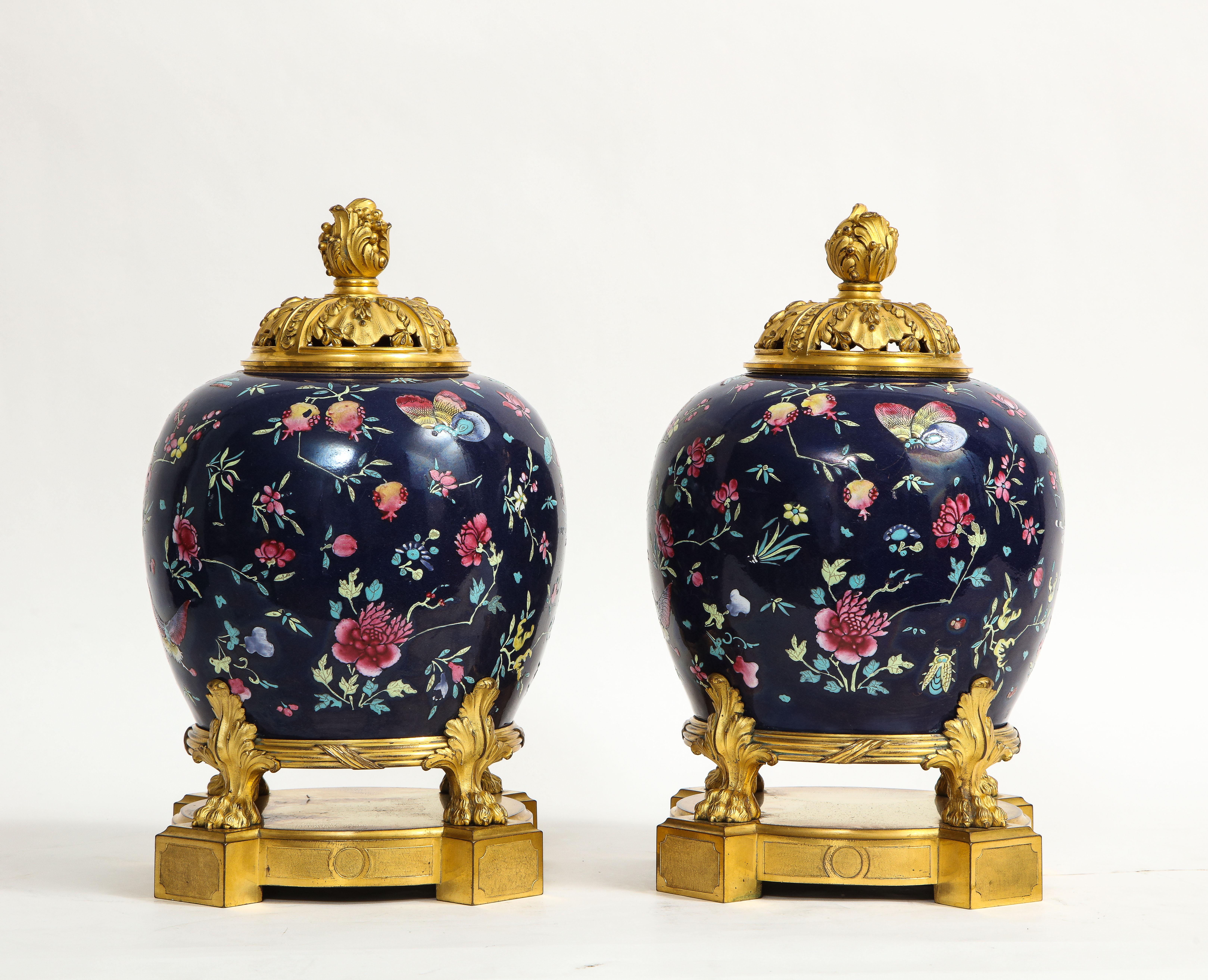 Fantastique paire de pots-pourris en porcelaine chinoise de la famille rose, montés en bronze doré, de style Louis XVI, du 19e siècle. Chaque corps en porcelaine de fond bleu foncé est magnifiquement émaillé à la main de magnifiques motifs de la