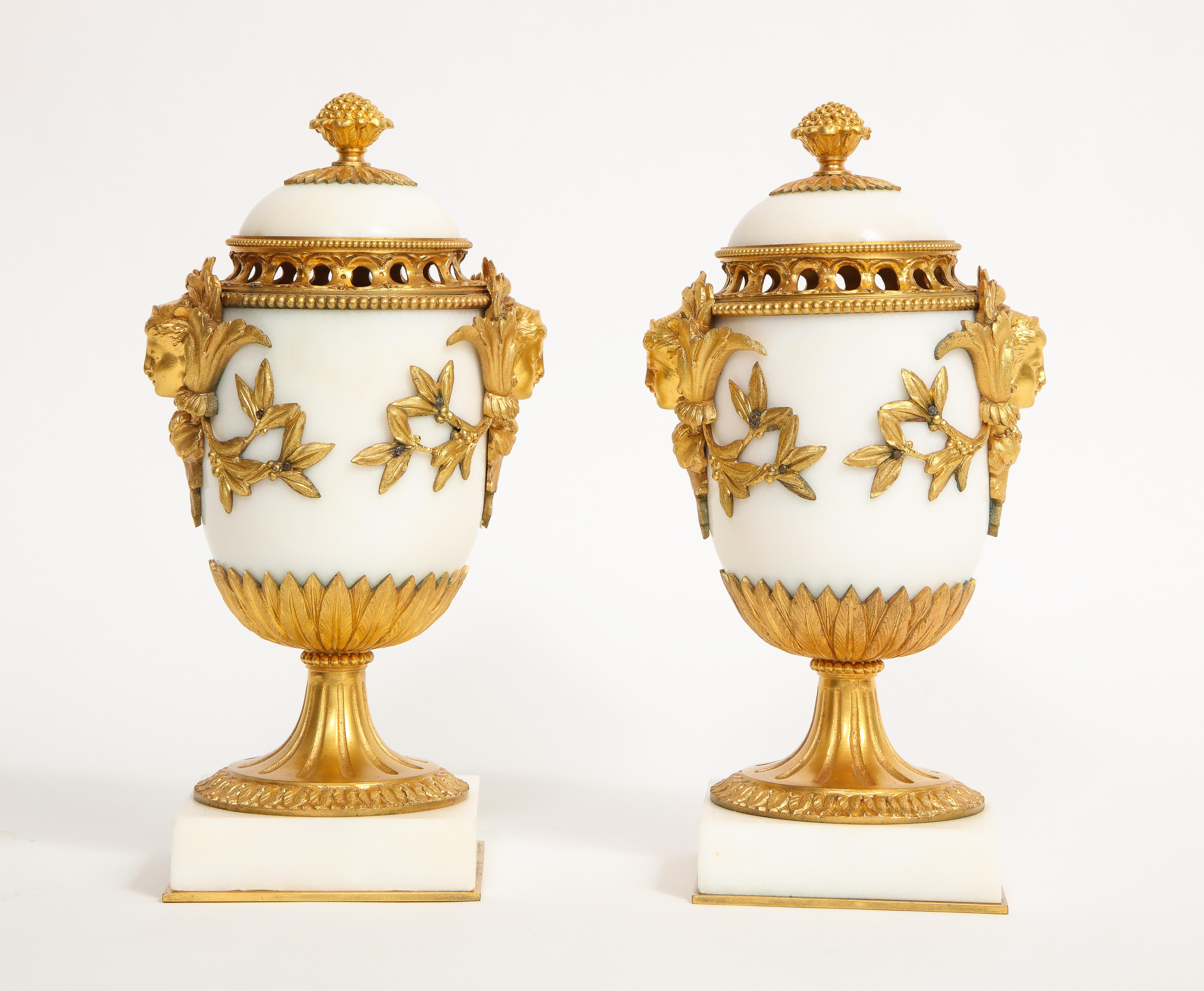 Una magnifica coppia di potpourri in bronzo dorato in stile Luigi XVI, attribuiti a Henry Dasson. Ognuno di essi è realizzato con la migliore qualità di marmo bianco di Carrara e con le migliori montature in bronzo dorato bicolore fuse, cesellate e