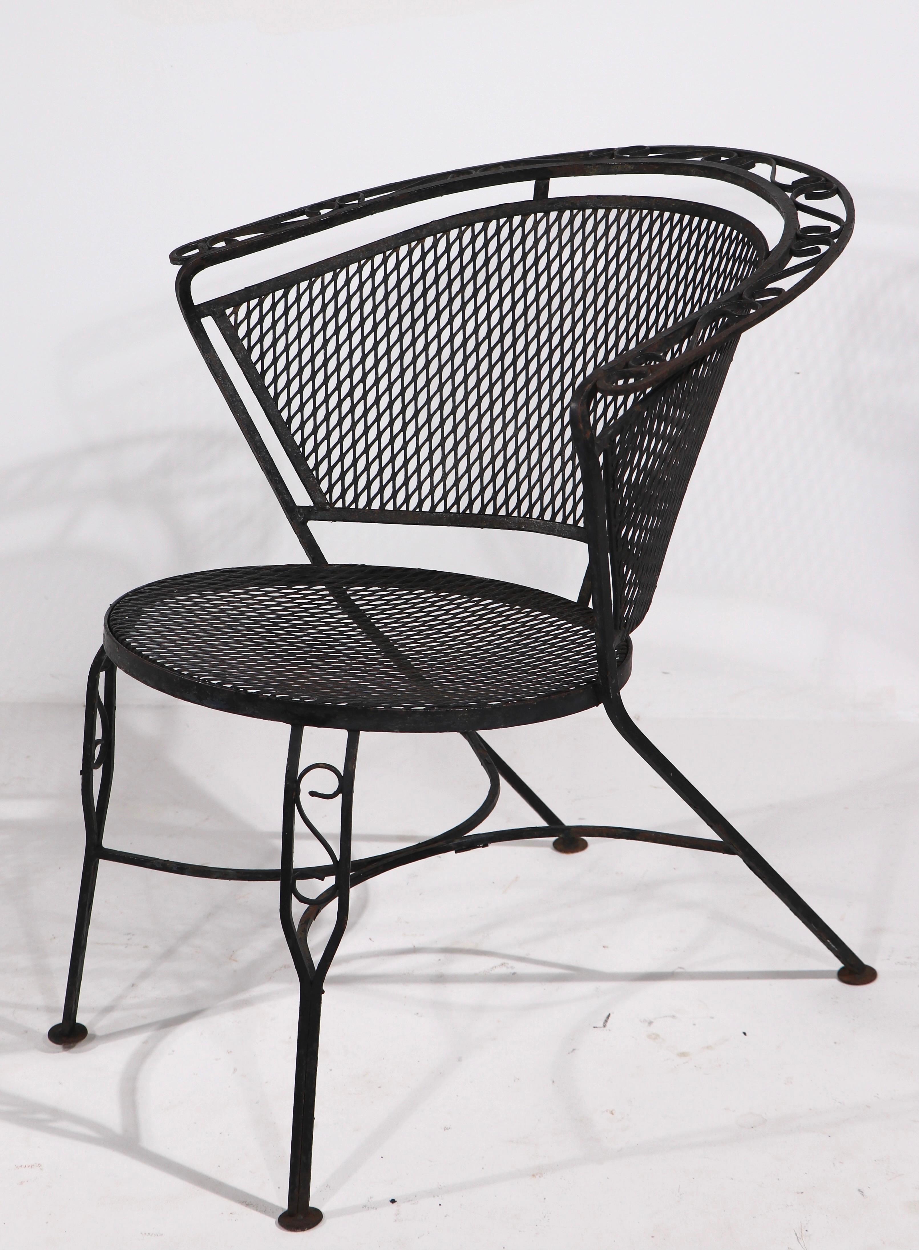 Chic and stylish pair of wrought iron garden, patio, poolside lounge chairs attributed to Salterini. The chairs have wrought iron frames, with metal mesh seats and backs. Both are in good original condition, free of structural damage or repairs,