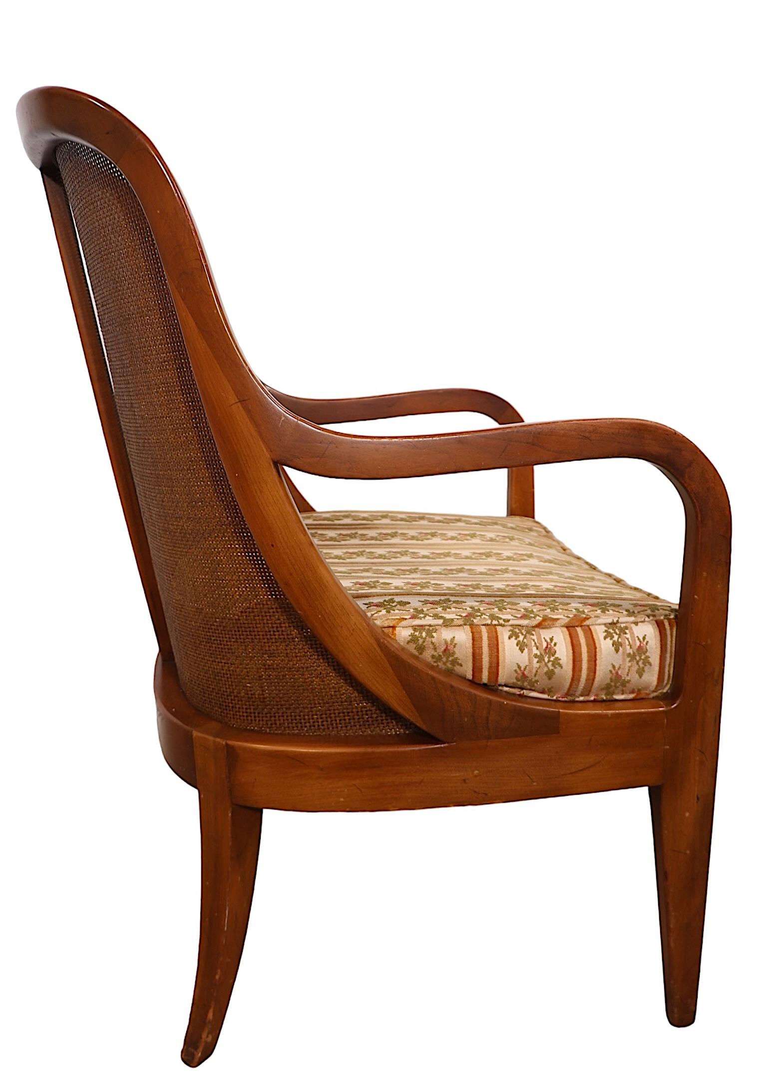 Vistosa pareja de tumbonas bajas con respaldo de caña atribuidas a Michael Taylor para The  Baker Furniture Company, hacia 1950/70. Las sillas tienen  Armazón de cerezo macizo con estilizados brazos curvos esculpidos que continúan en el respaldo de