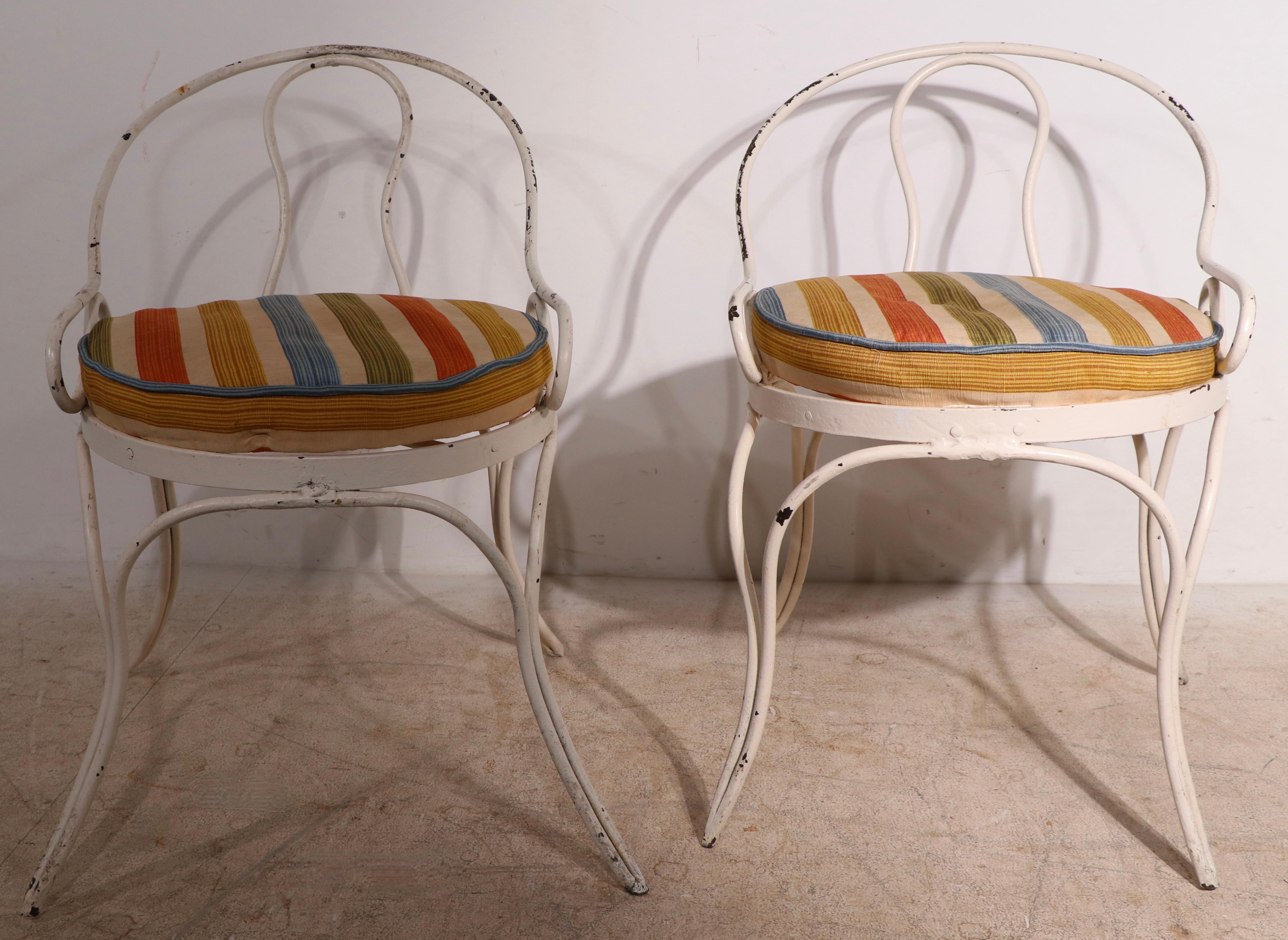 Pair of unusual low slung slipper, boudoir, occasional chairs having wrought iron frames and upholstered seats. The chairs are in good overall condition, however both are slightly misshapen, hence the seats do not fit exactly in position. The