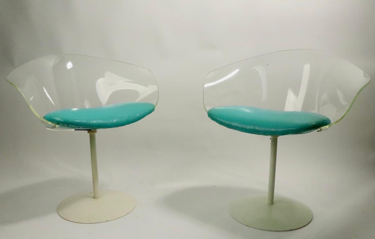 Stylish pair of swivel chairs each having a curved Lucite back with vinyl pad seat, mounted on a pedestal base. Both are in very good, clean original condition, showing slight cosmetic wear to white paint finish on bases, normal and consistent with