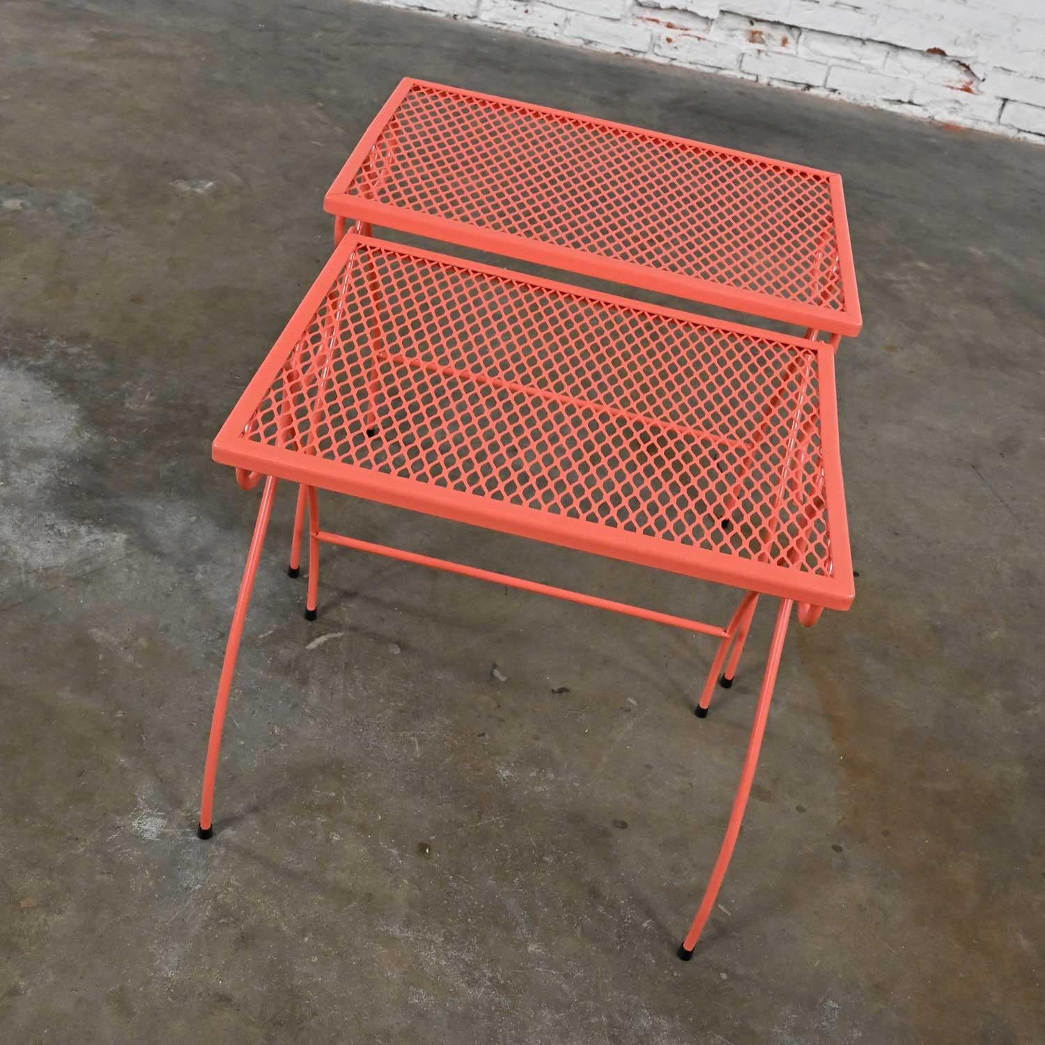 Fabulous vintage Mid-20th Century MCM (Mid-Century Modern) coral painted metal wire famed with expanded metal mesh top outdoor nesting tables, a pair. Beautiful condition, keeping in mind that these are vintage and not new so will have signs of use