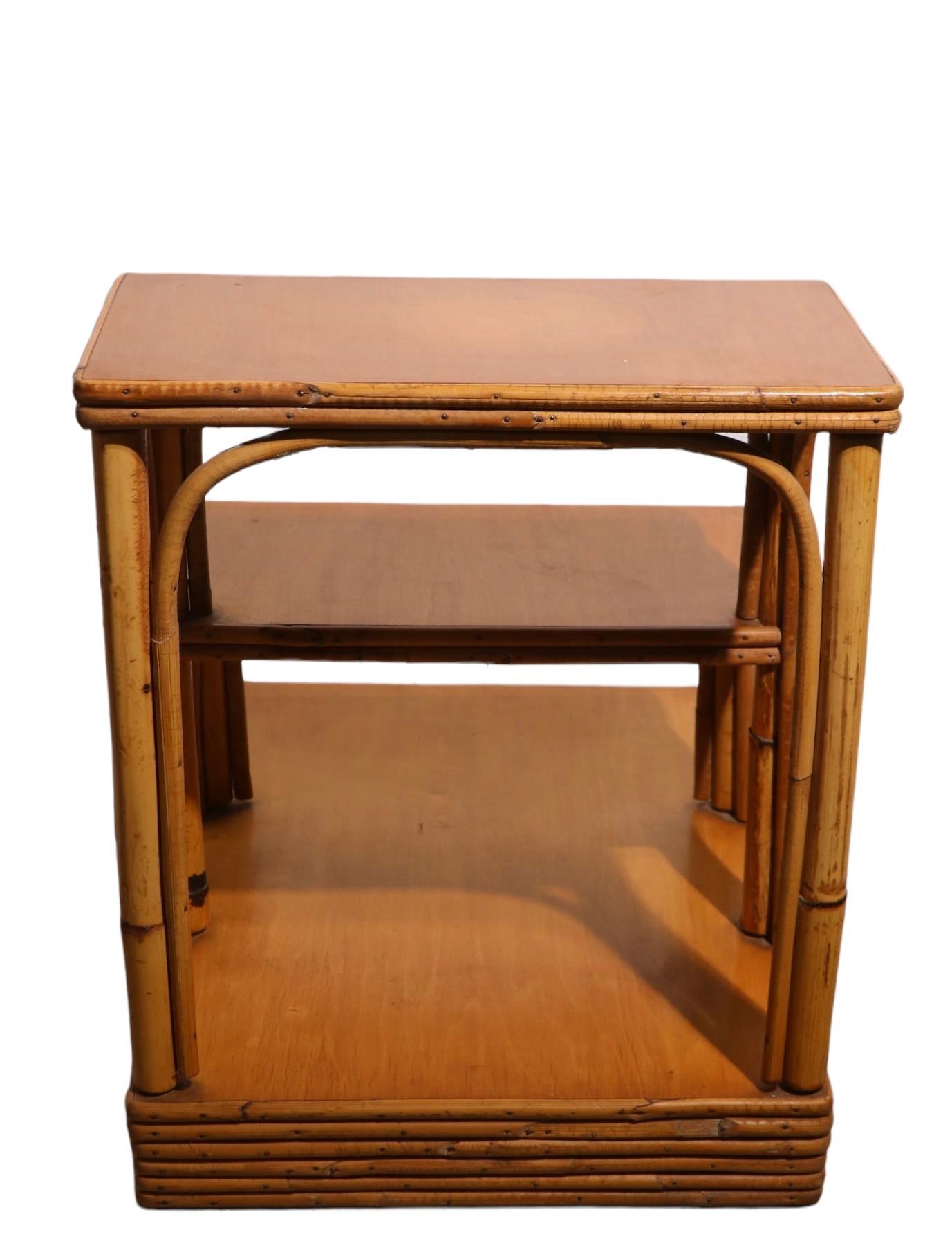 Chic pair of bamboo step end tables by noted the American furniture company Ficks Reed. Each table has a banded bamboo base, with three graduated tiered shelves. Known for top quality craftsmanship, and high style design, Ficks Reed produced high