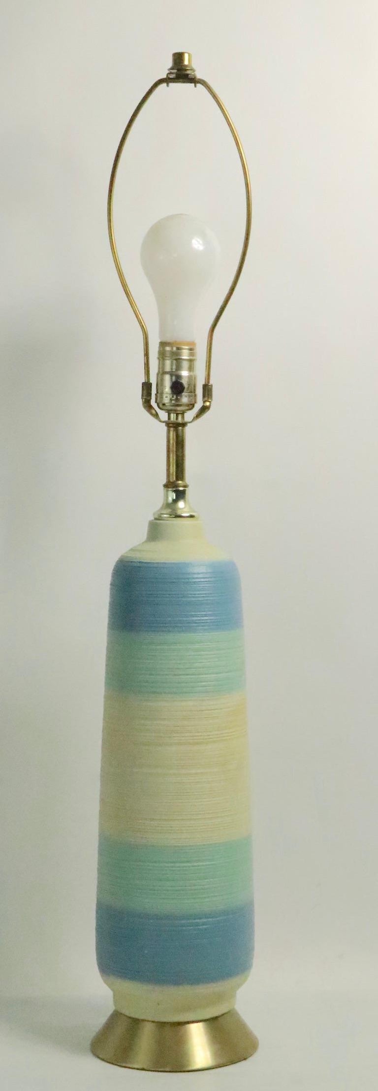 Pair of stylish midcentury ceramic table lamps having a textured surface with graduated color bands. Both are in very good, original and working condition showing only light cosmetic wear normal and consistent with age. Both lamps accept standard