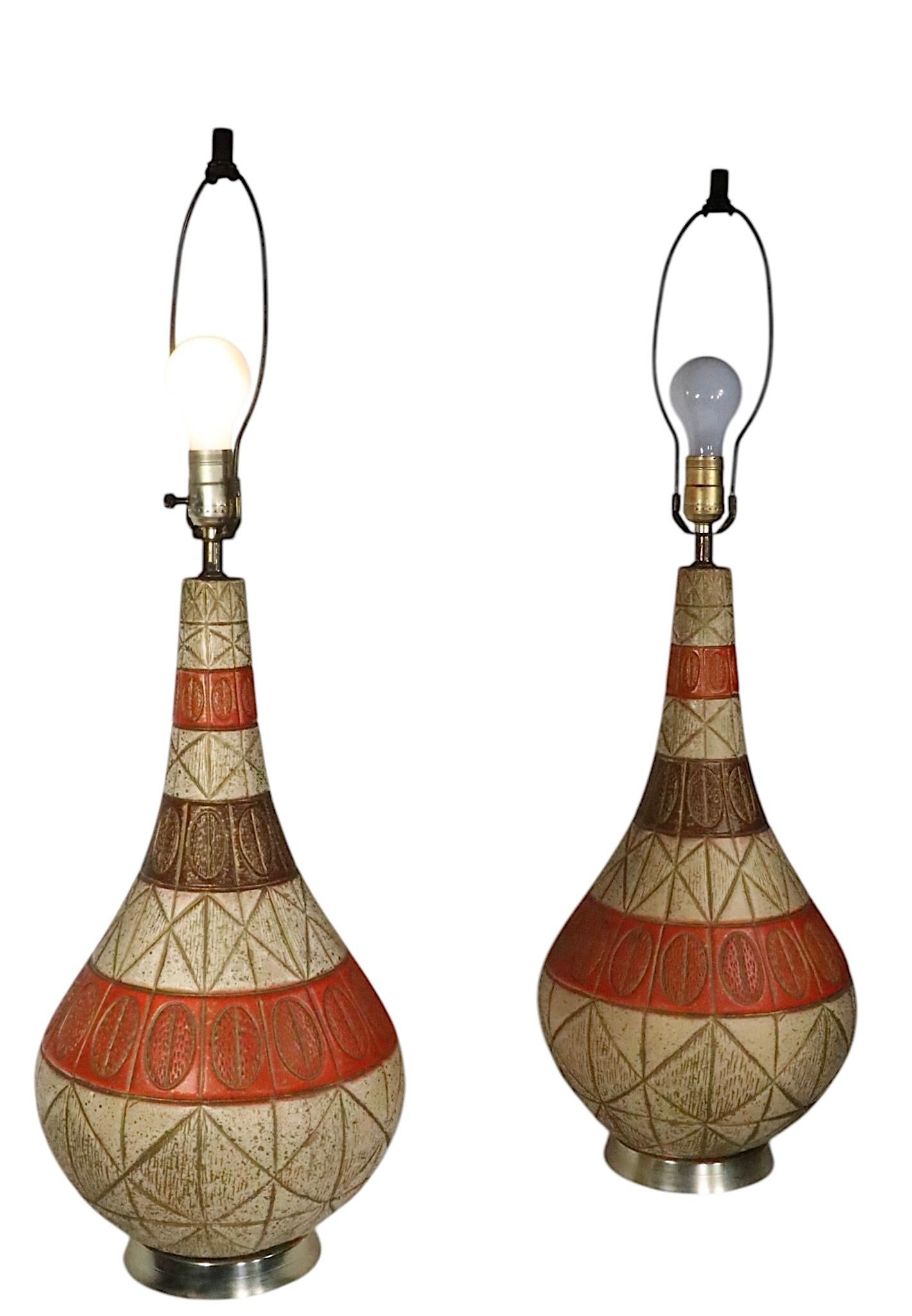 Paire de lampes de table en céramique du milieu du siècle, avec des corps en forme de quilles de bowling, des surfaces texturées sgraffito dimensionnelles dans une finition de glaçure sable, orange et or. Fabrication américaine, dans le style