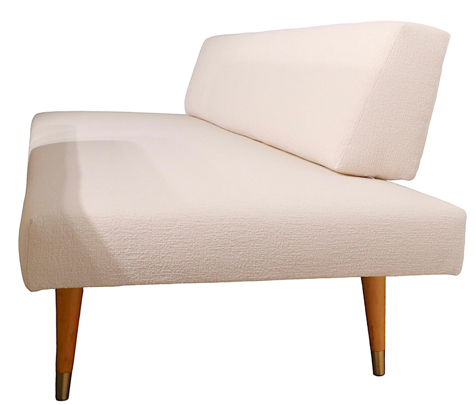 Classic pair of mid century daybed sofas, newly reupholstered in chic off white boucle fabric. The sofas feature asymmetrical backrest cushions, and upholstered seat cushions, on blonde tapered pole legs. Restored to like new condition, clean, ready