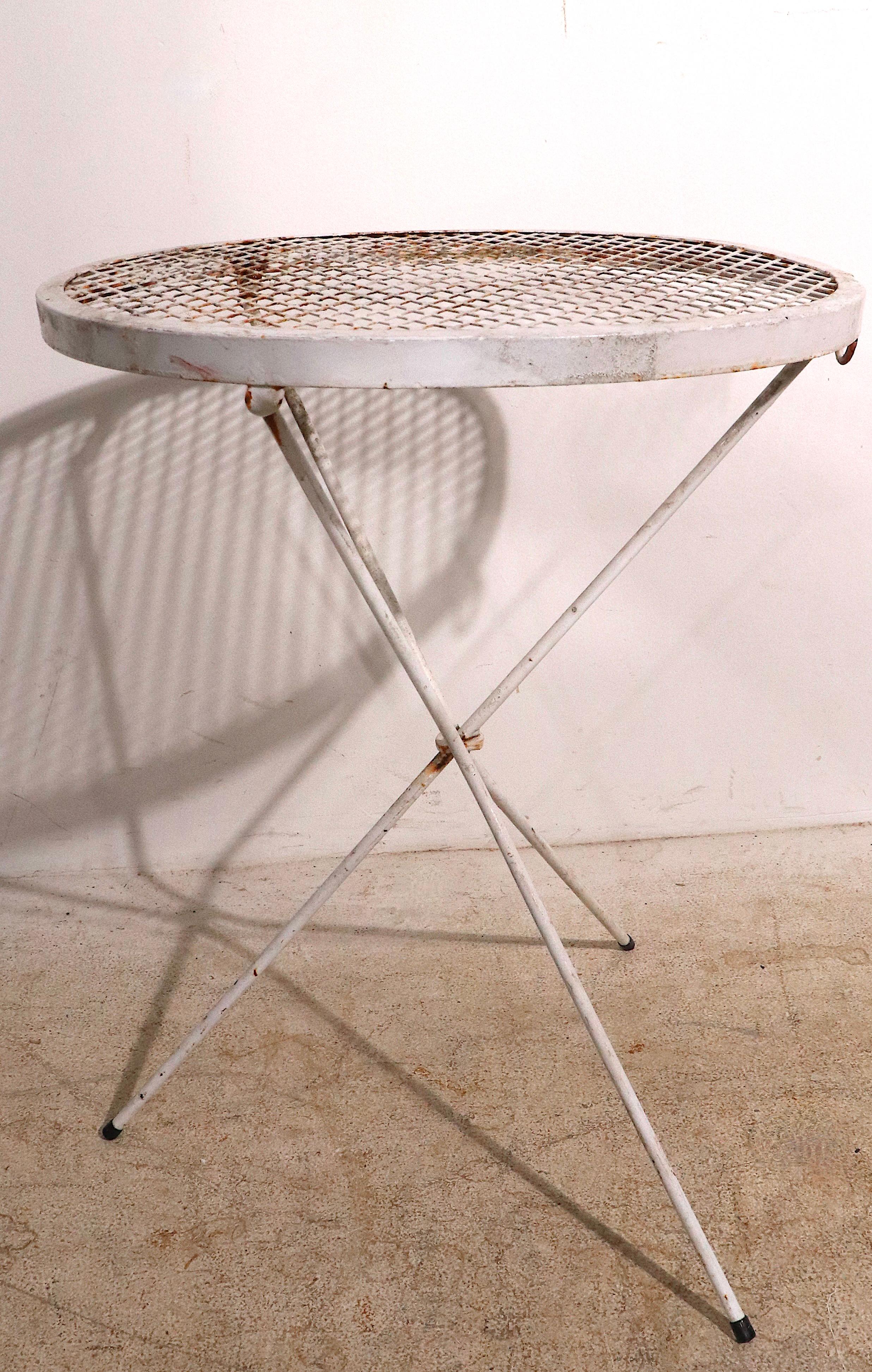 Chic architectural folding side, occasional, end tables, attributed to Salterini. Tripod legs, disk form metal mesh tops. These fun tables fold to flat, and can be hung on the wall for easy storage. Both are structurally sound and sturdy, both show