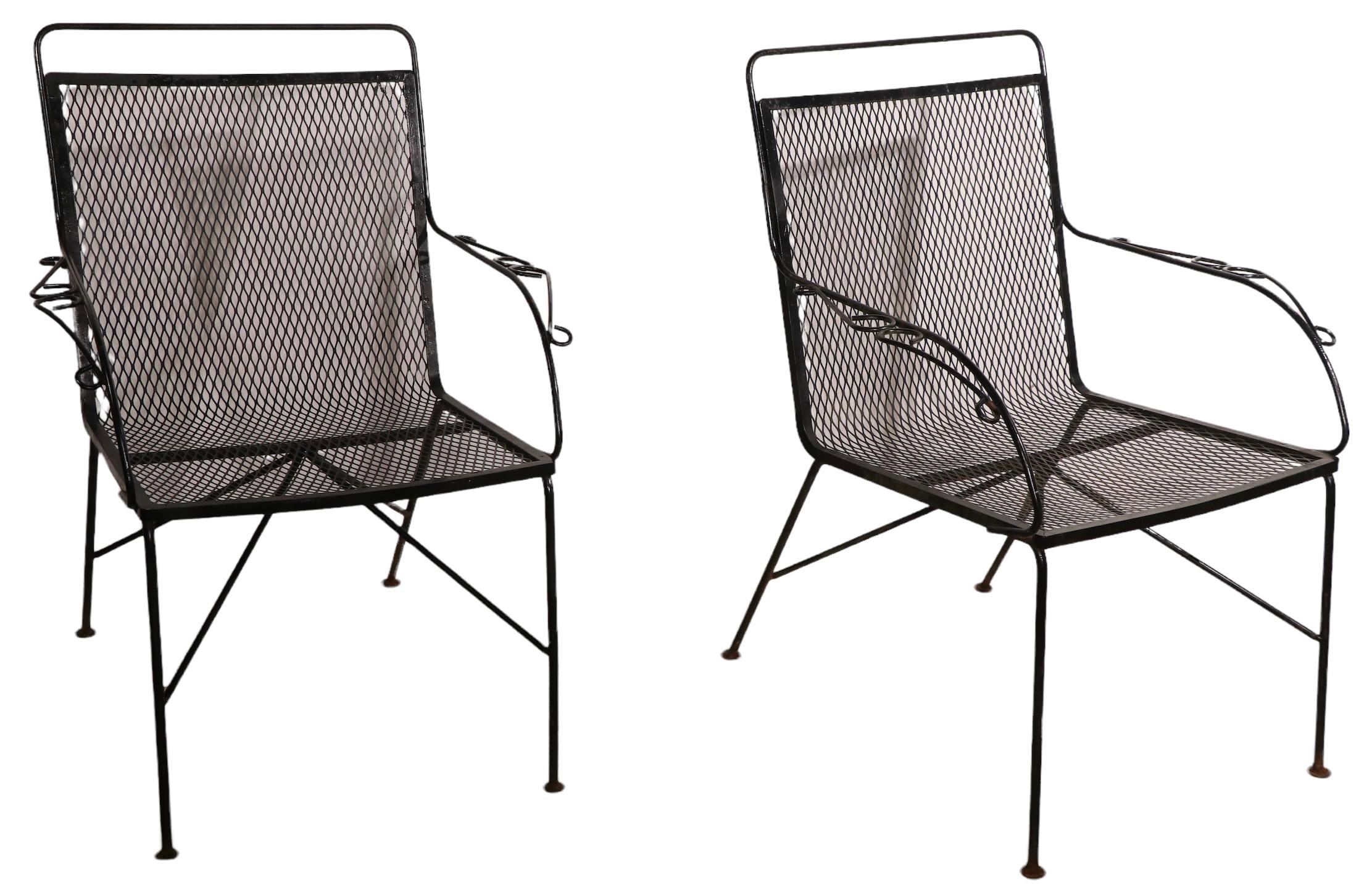 Pair of mid-century garden, patio, poolside chairs constructed of wrought iron and metal mesh. These can function as dinning, or lounge chairs, both are in good, original condition, showing only light cosmetic wear, normal and consistent with age.