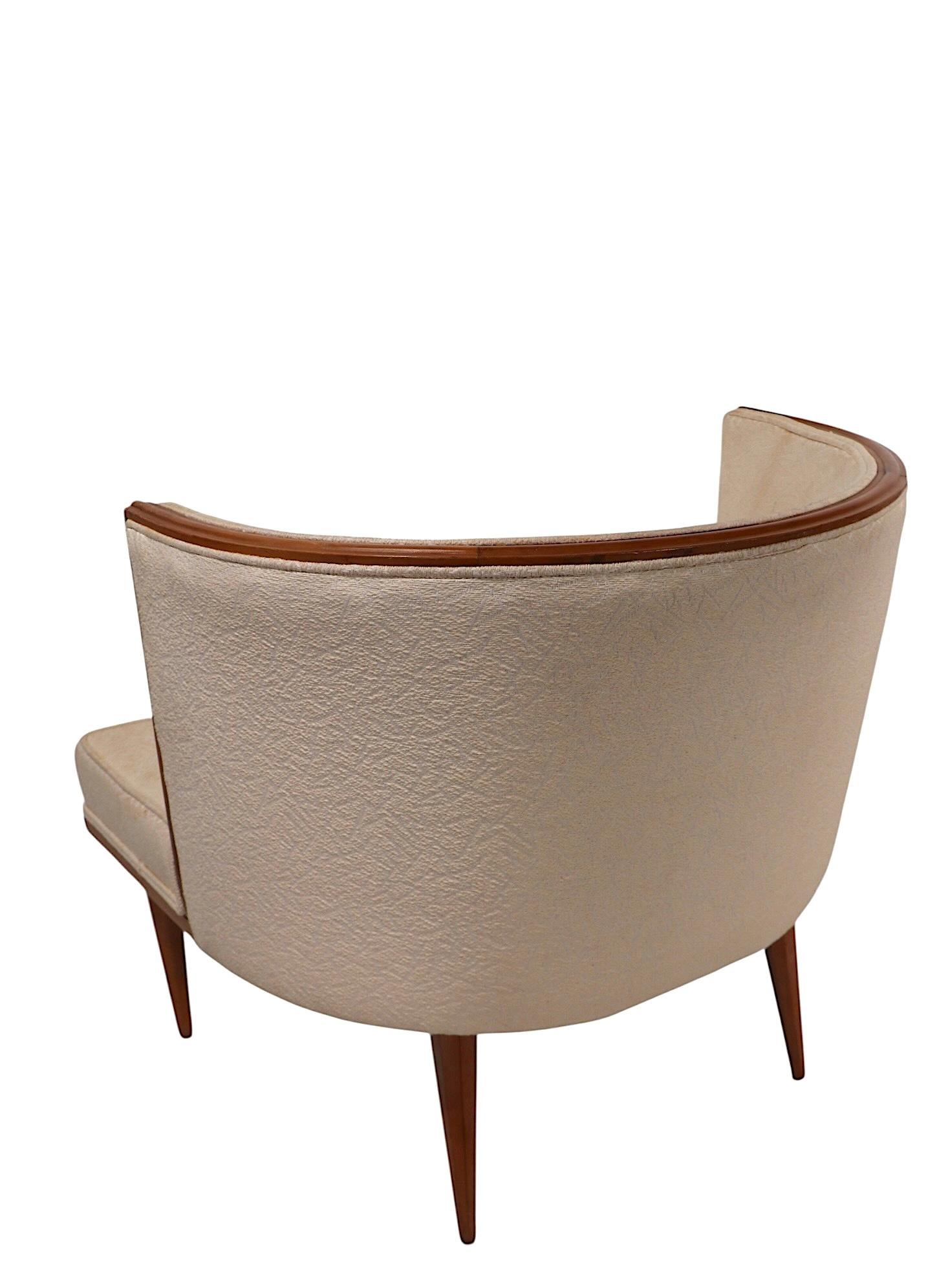 Exceptional pair of mid century tub chairs, having semi circular wraparound backs with elegant  detailed wood trim molding. The upholstered seats are mounted on an exposed wood platform, having tapered faceted pole legs. These sophisticated chairs