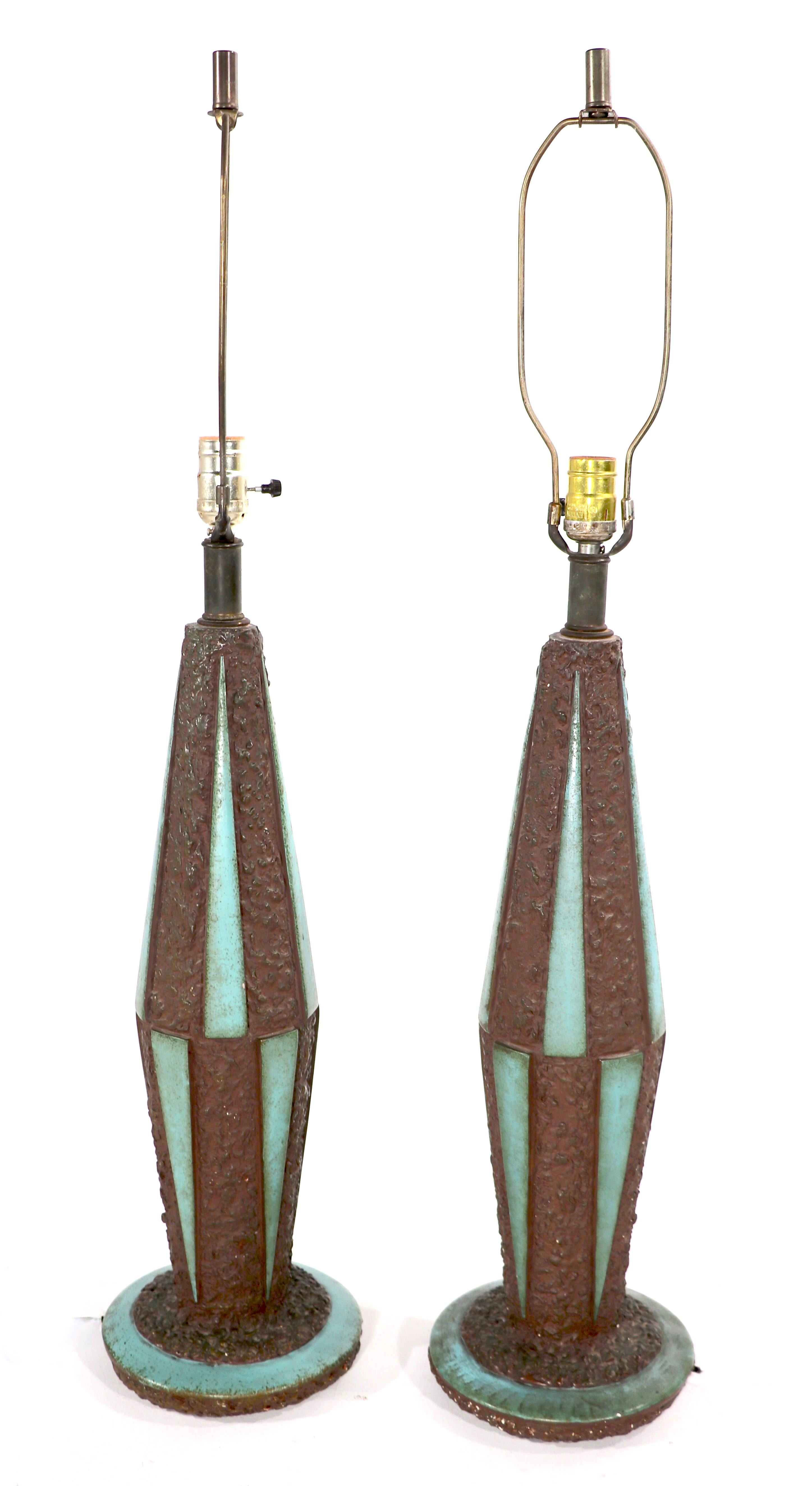 Stylish pair of Mid-Century table lamps having textured ceramic surfaces with smooth glaze triangular panels. The textured ground is a bronze / brown tone, the triangular panels are turquoise in color Both are in good original working condition,