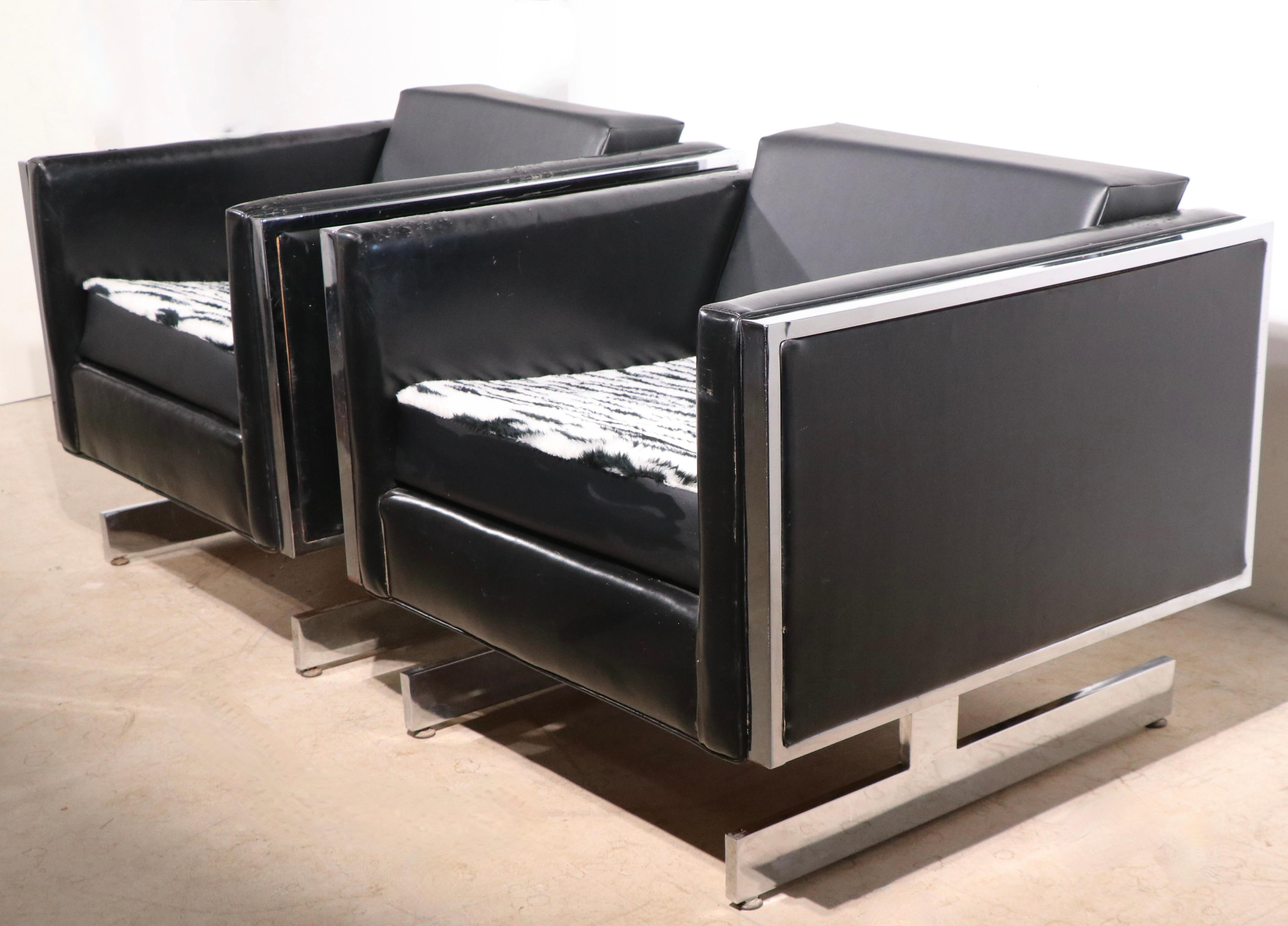 Chic pair of black and chrome cube form lounge chairs, by the Patrician Furniture Company circa 1970's. The chairs feature angular chrome legs, with a cube form seat, of black vinyl and faux leopard, or cheetah, fur on the seats. The cars also have