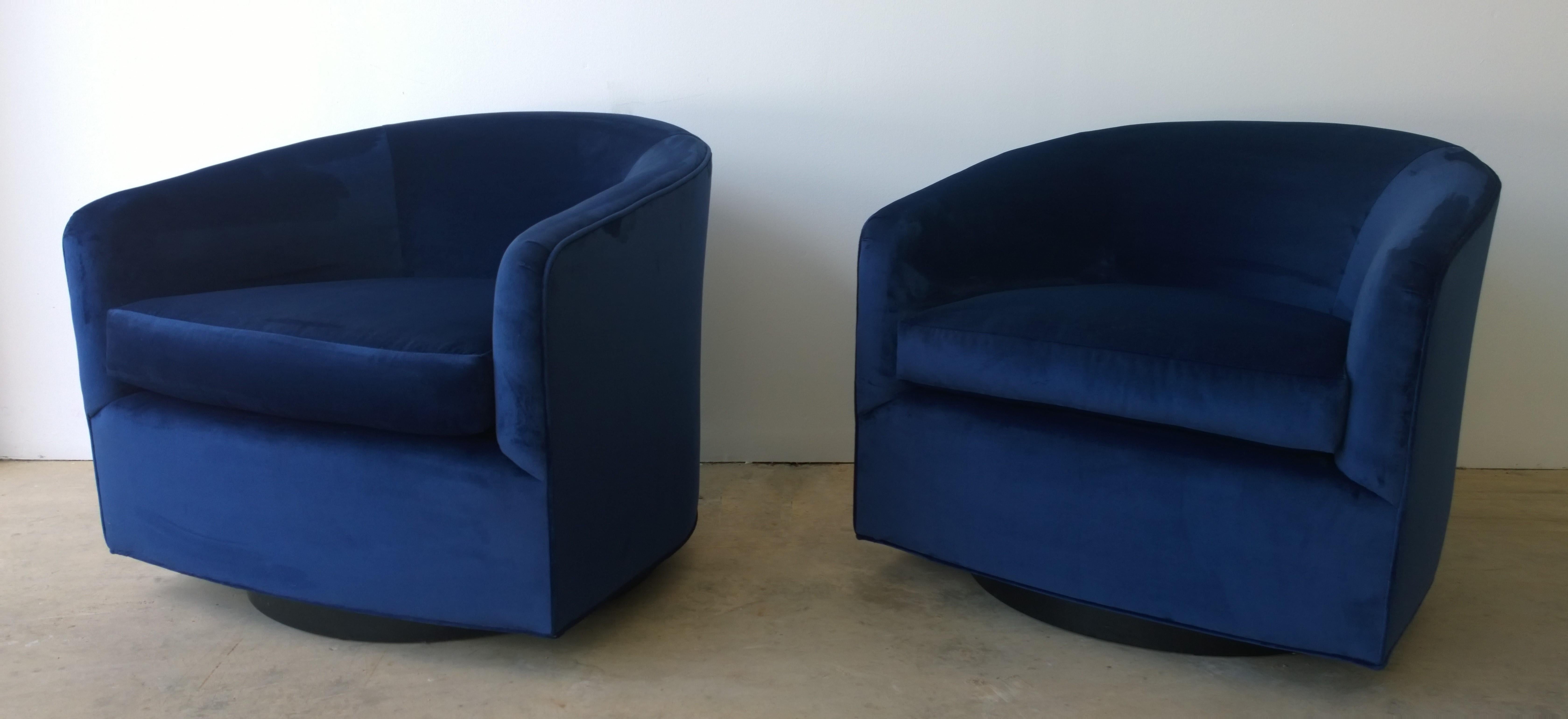 Offered is a pair of Mid-Century Modern Milo Baughman style swivel chairs with ebony wood veneer base upholstered in a new sapphire blue cotton velvet. This pair of swivel chairs exudes luxury in style, material and color. The comfort and proportion