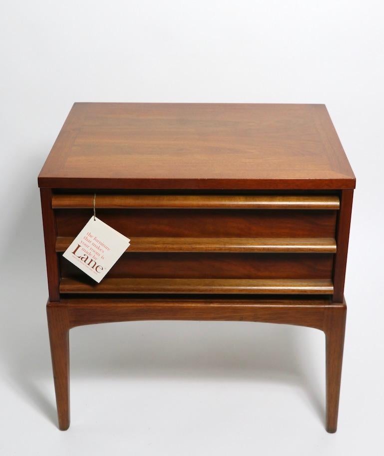 Stylish midcentury night tables, rhythm by Lane Furniture. Architectural design, American made in the Danish modern style. Constructed of solid walnut, having one deep drawer with three horizontal wood elements on the front.
These nightstands still