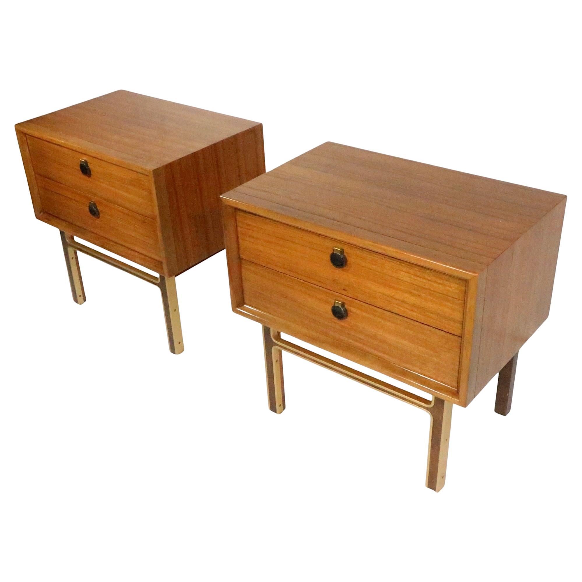 Sharp pair of classic Mid Century nightstands, made in the USA, circa 1950/60's. The night tables feature two drawers, each with a drop style tab pull. The cases are raised on stylized wood and anodized aluminum gold tone legs. Both are structurally