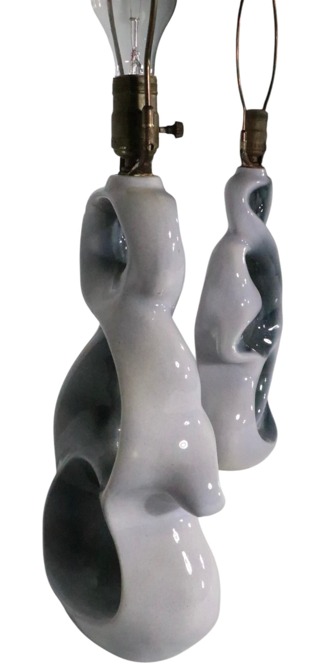 Paire exceptionnelle de  Lampes de table en céramique modernes du milieu du siècle, en excellent état d'origine, propres et prêtes à l'emploi. Les lampes présentent des formes céramiques fluides entrelacées, avec des fenêtres d'espace ouvert au