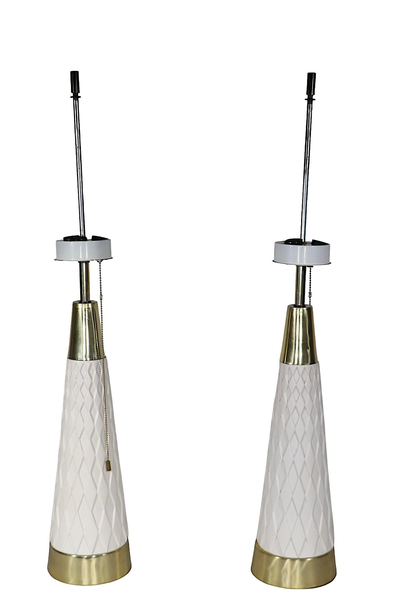 Chic pair of late 1950's - early 60's table lamps, designed by Gerald Thurston for Lightolier. The lamps feature ceramic  tapering conical bodies having a raised relief diamond quilted pattern surface in white mat glaze finish, with brass colored