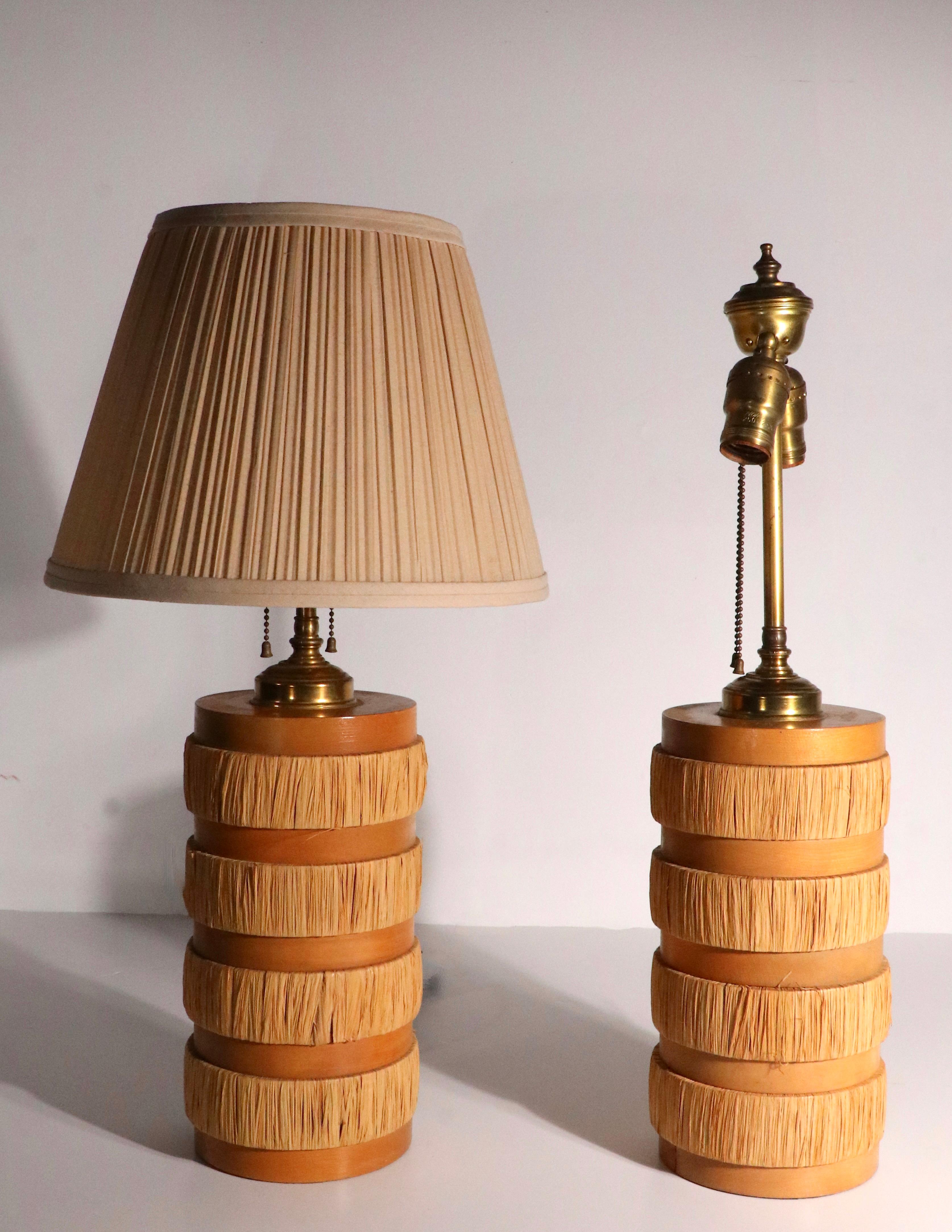 Paire de lampes de table du milieu du siècle en disques de bois empilés avec des disques alternés de joncs enveloppés. Chaque lampe possède deux douilles à chaîne, chacune fonctionnant indépendamment pour permettre une intensité lumineuse élevée ou