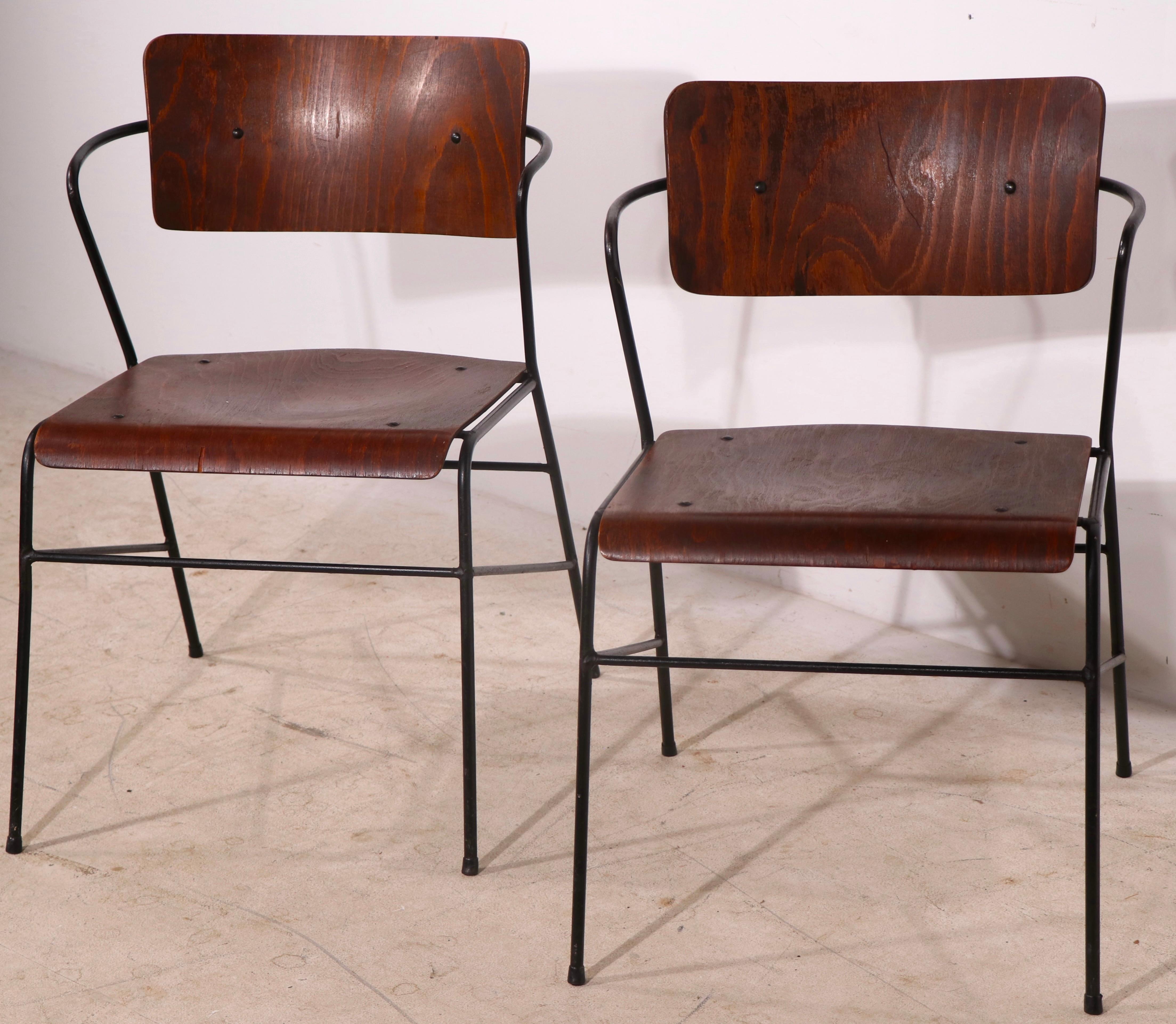 Chic architectural pair of mid century dining height arm chairs, having wrought iron frames with formed plywood seats and backs. Both chairs are structurally sound and sturdy, both show some cosmetic wear normal and consistent with age.