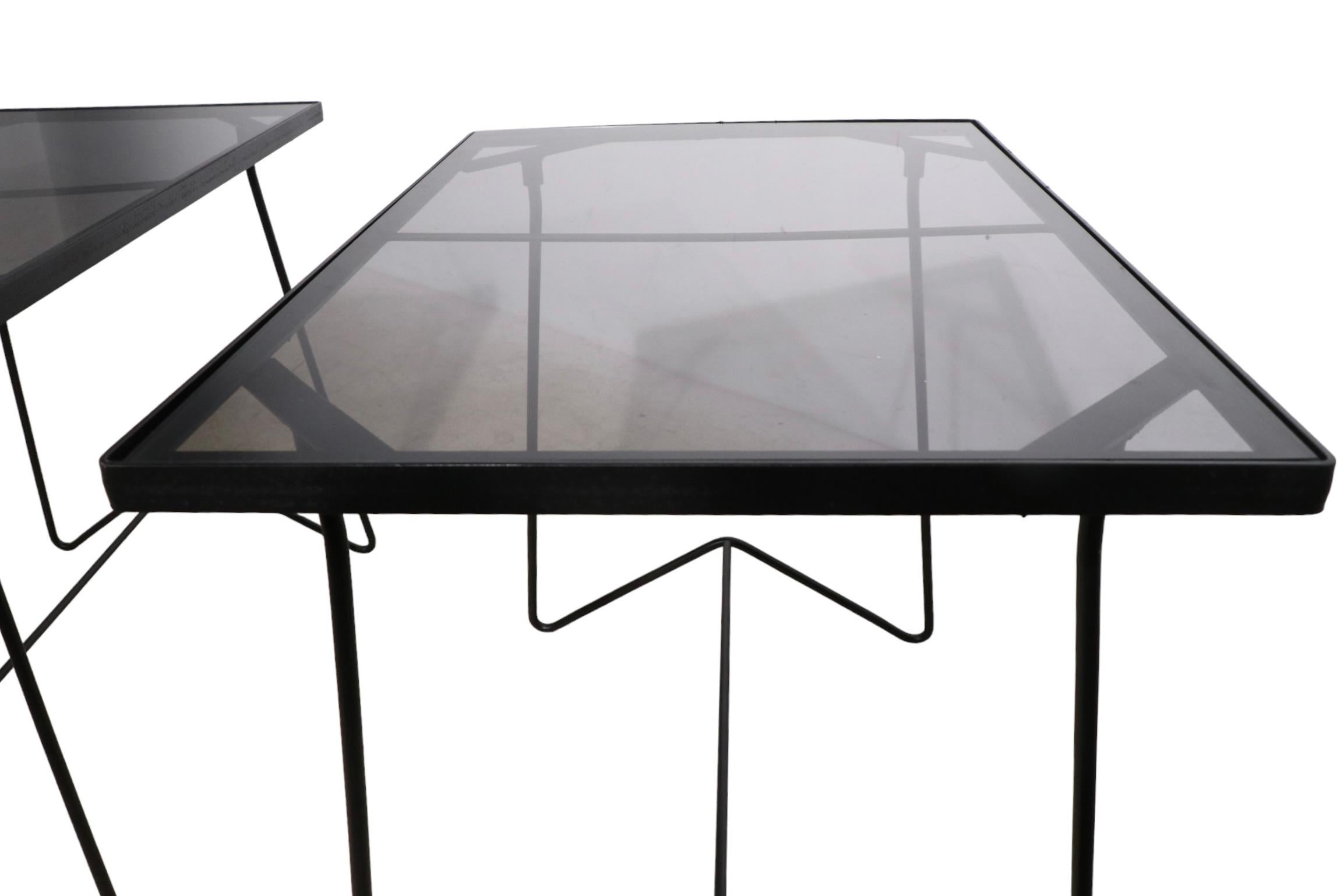 Pr. architectural side, or end tables having wrought iron frames, and tinted glass tops. These chic tables are suitable for indoor, outdoor, and or patio, poolside, garden use. Both have been recently repainted black, and the glass tops are also