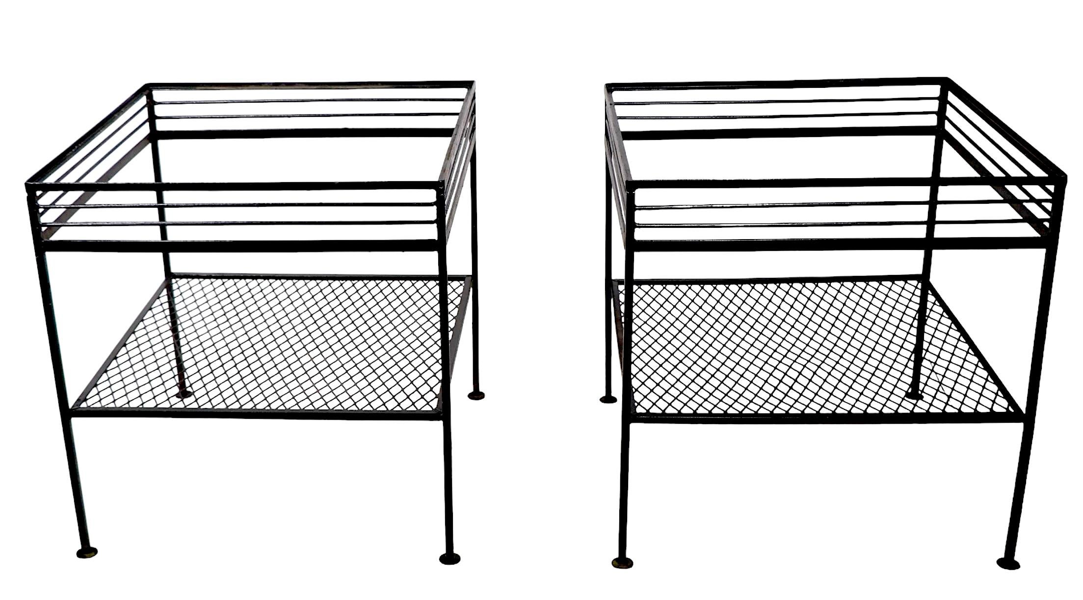 Sophisticated, architectural pair of wrought iron and metal mesh side, or end tables, attributed to The Woodard Furniture Company, in the style of Avard, McCobb, Salterini etc. This pair features repeating  horizontal rods, and a second lower shelf