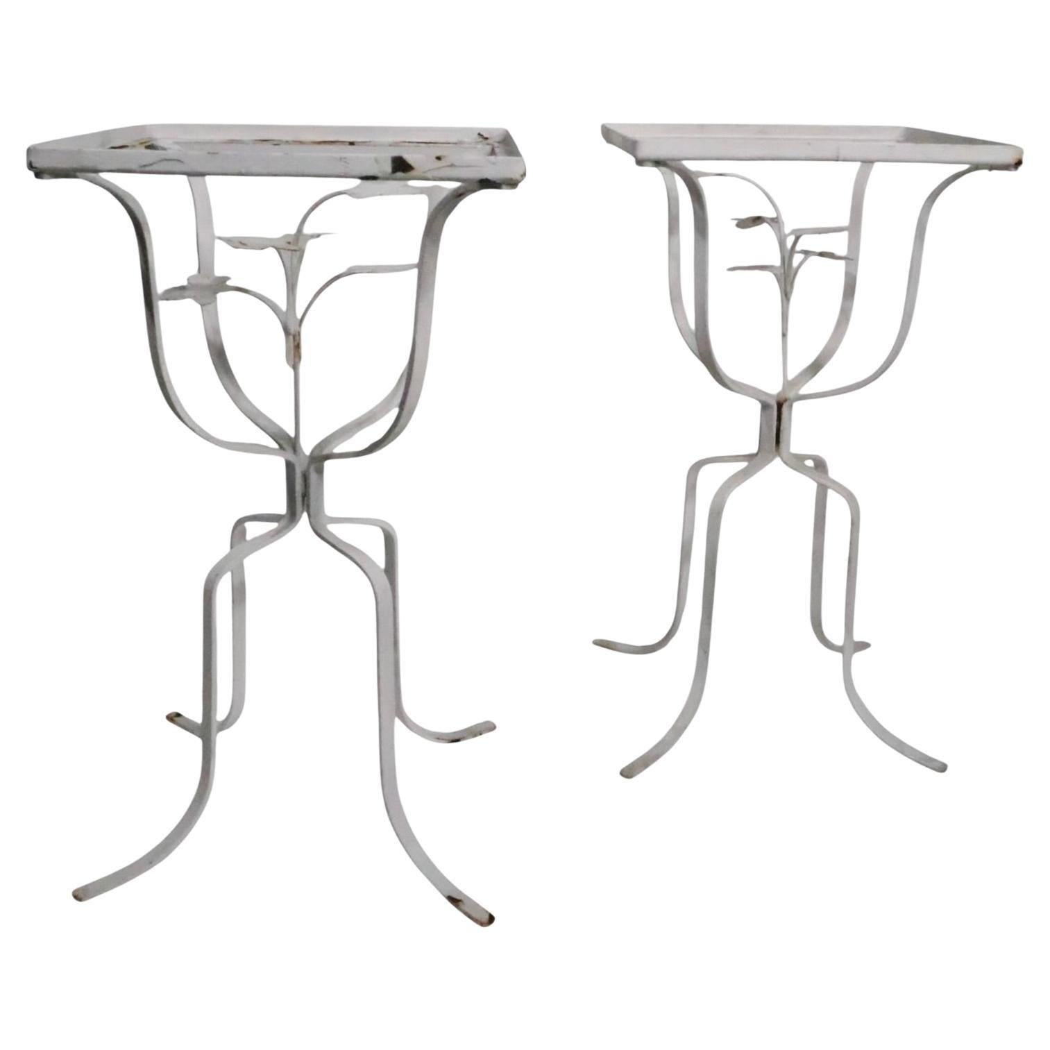 Encantador par de  Mesas auxiliares decorativas de hierro forjado, soportes para bebidas, fabricadas en EE.UU., hacia 1950/60 posiblemente por la Woodard Furniture Company, sin firmar.
 Las mesas presentan una planta metálica en el centro, aceptan