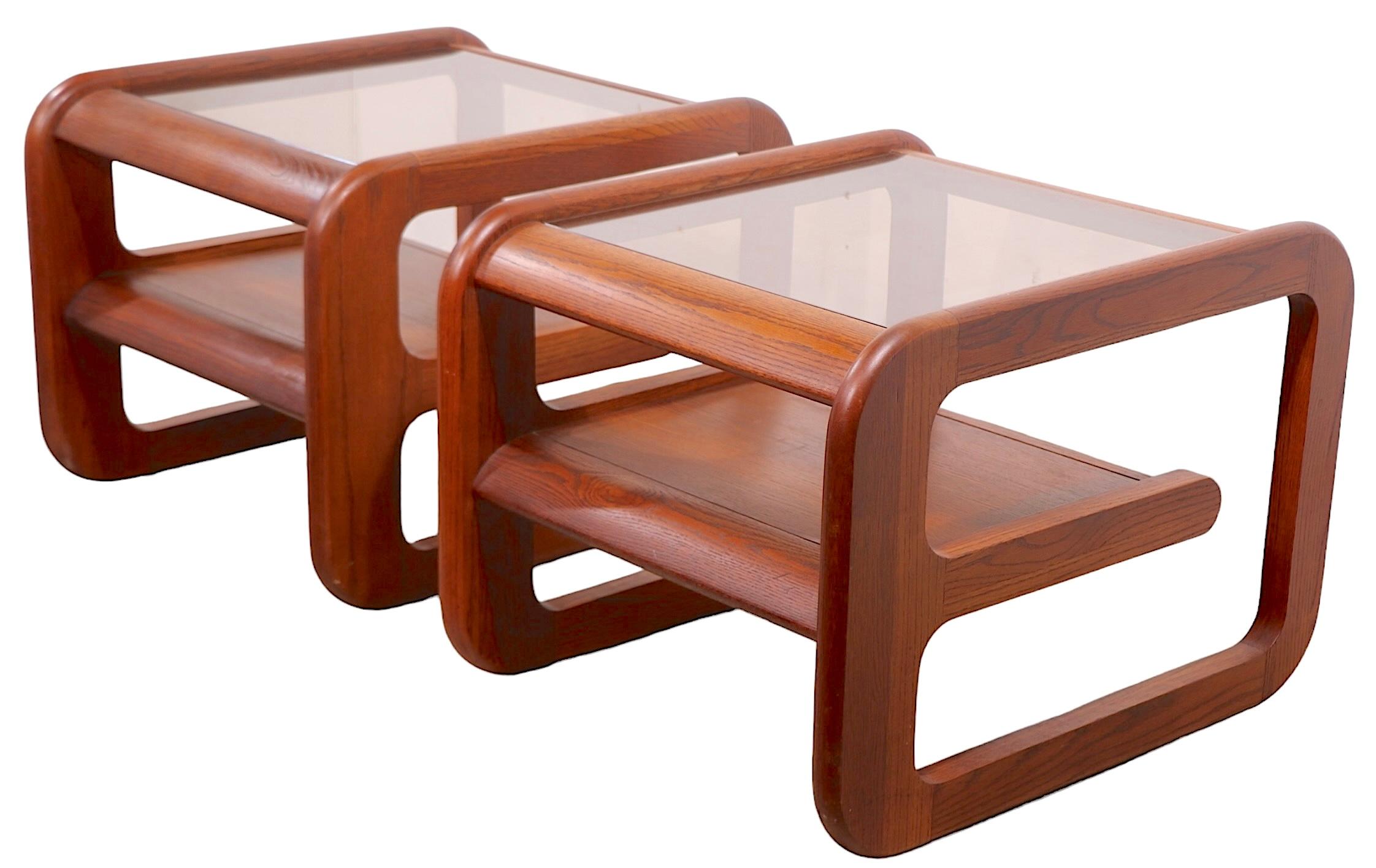 Pair of stylish side, or end tables designed by Lou Hodges for The  Lane Alta Vista  Furniture Company, circa 1970's. These chic tables feature  solid oak frames, with smoked, or tinted, glass tops. Both tables are in very good, clean, ready to use