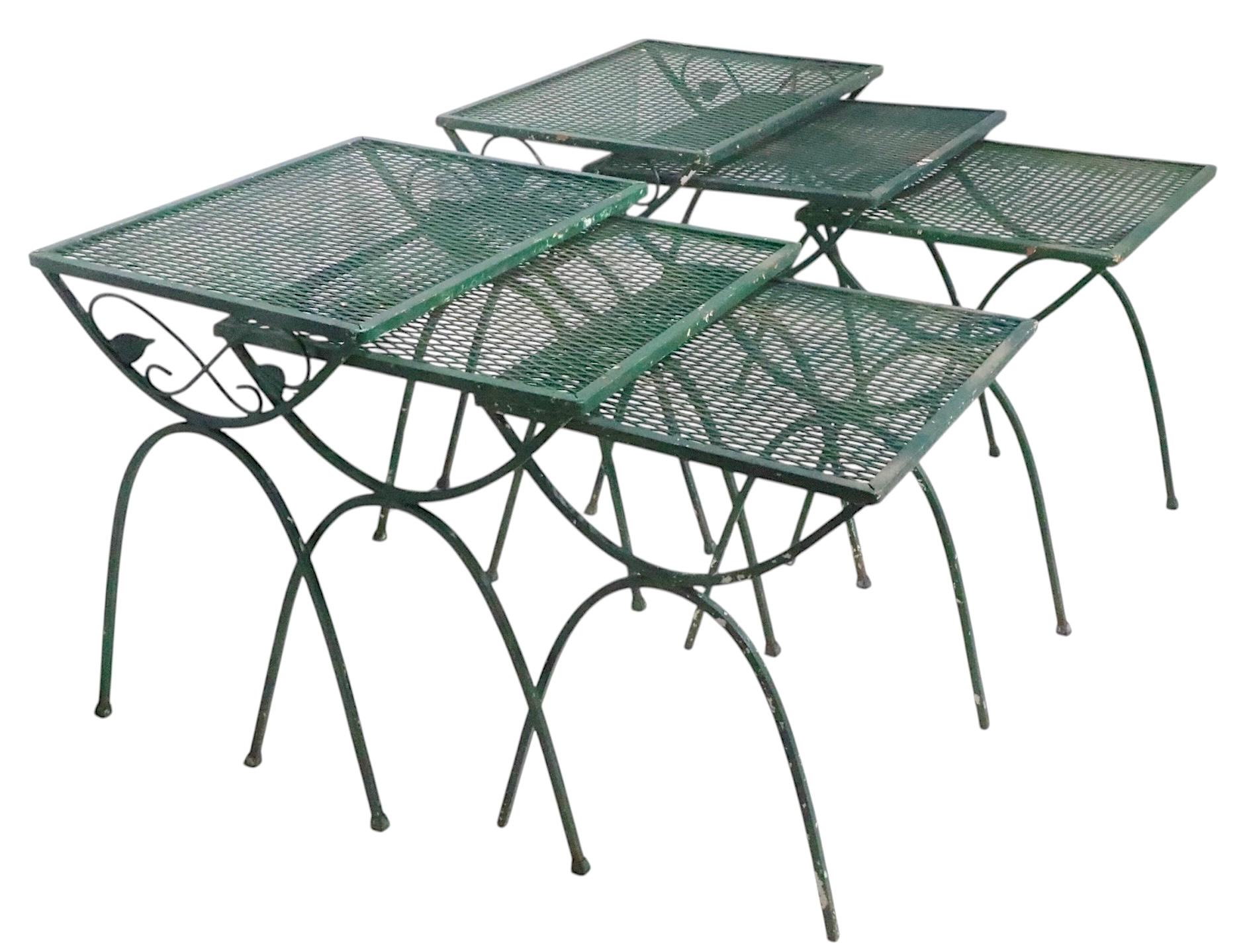 Pair of three pice nesting tables, probably made by the Woodard Furniture Company, unsigned. The tables feature opposing U shaped legs, the larger one has decorative foliate design metalwork. The tops are constructed of metal mesh. It  is unusual to