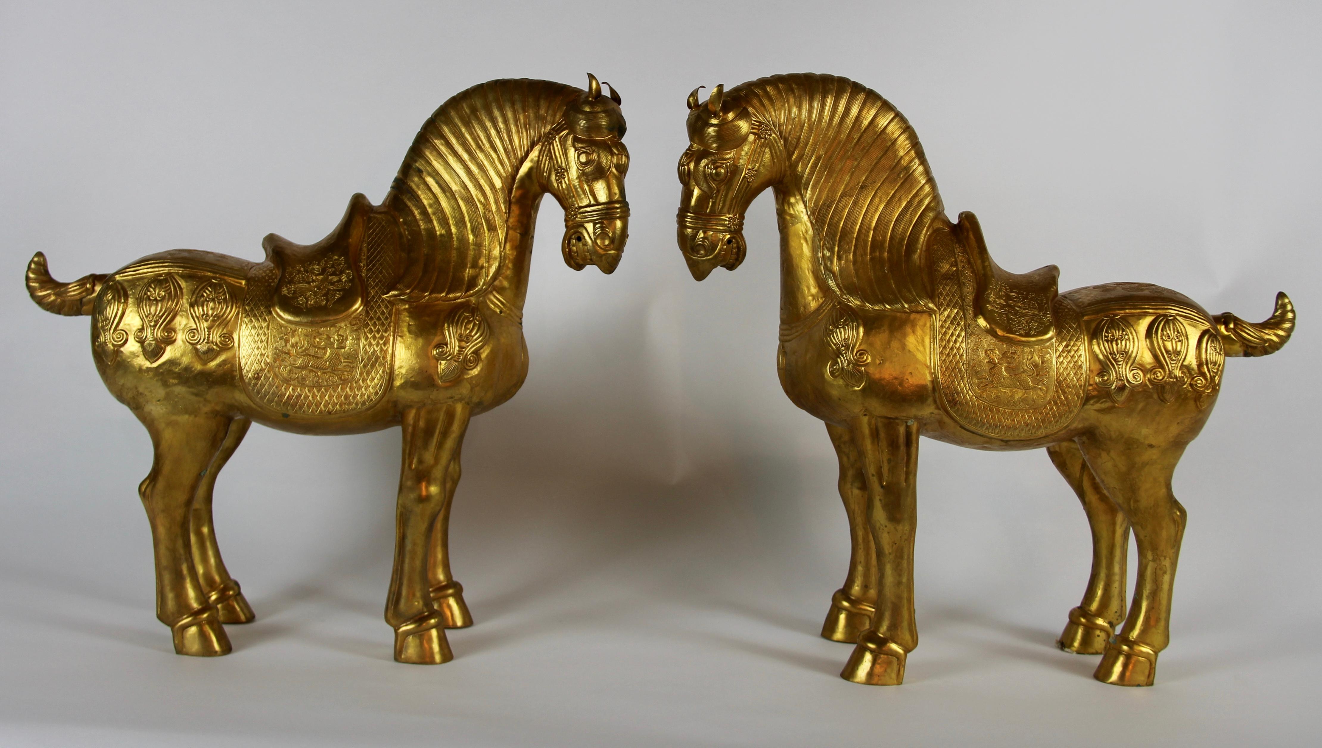 A fabulous, large, and quite decorative pair of Chinese orientalist design gilt bronze royal horses elaborately detailed with Chinese motifs. Each horse is beautifully cast and finished with gilt decoration. The saddles and all other areas of the