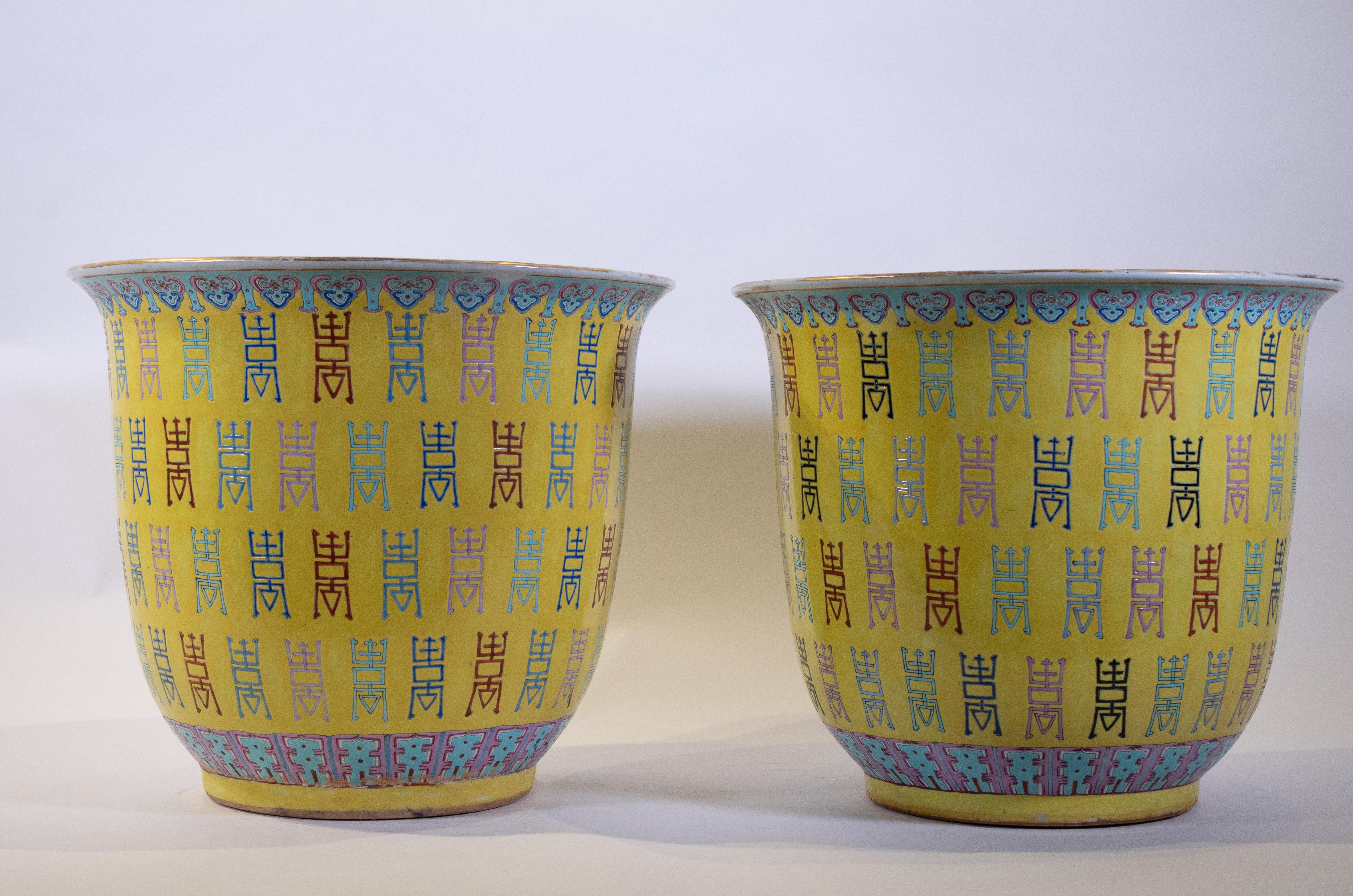 Une fabuleuse, grande et décorative paire de jardinières/vases en polychrome d'exportation chinoise Famille rose à fond jaune impérial. Chacune est magnifiquement peinte dans des émaux de fond jaune impérial et peinte à la main avec des caractères