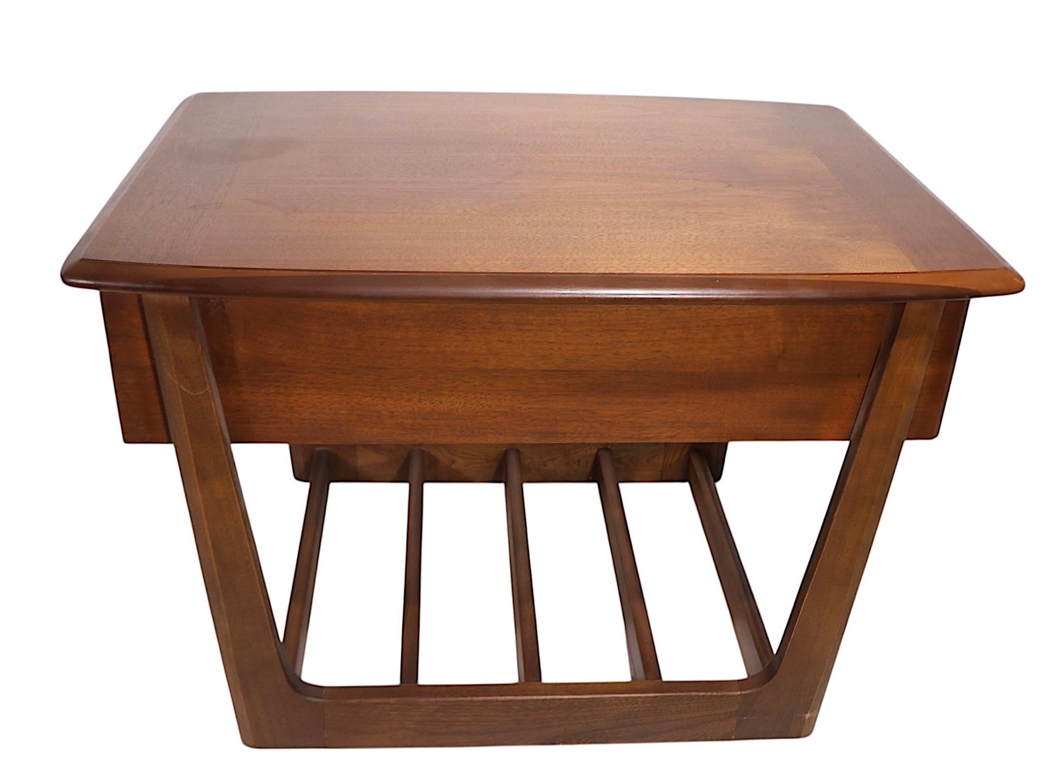 Pair of stylish Mid Century side, or end, tables made by the Lane Furniture Company, circa 1950/60's. Then tables feature a breadboarded style top over one drawer, supported by a sleigh form base with a slatted lower shelf for addition storage. Both