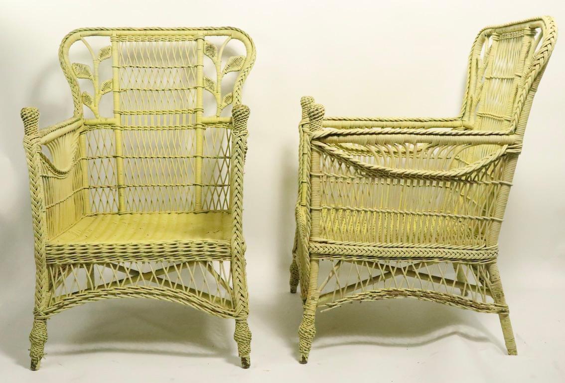 Extraordinary pair of ornate and decorative wicker lounge, armchairs, having woven leaf foliate backs, and finial form handgrips. Both chairs are in very fine condition, sturdy, solid and ready to use, both show inconsequential cosmetic wear, minor