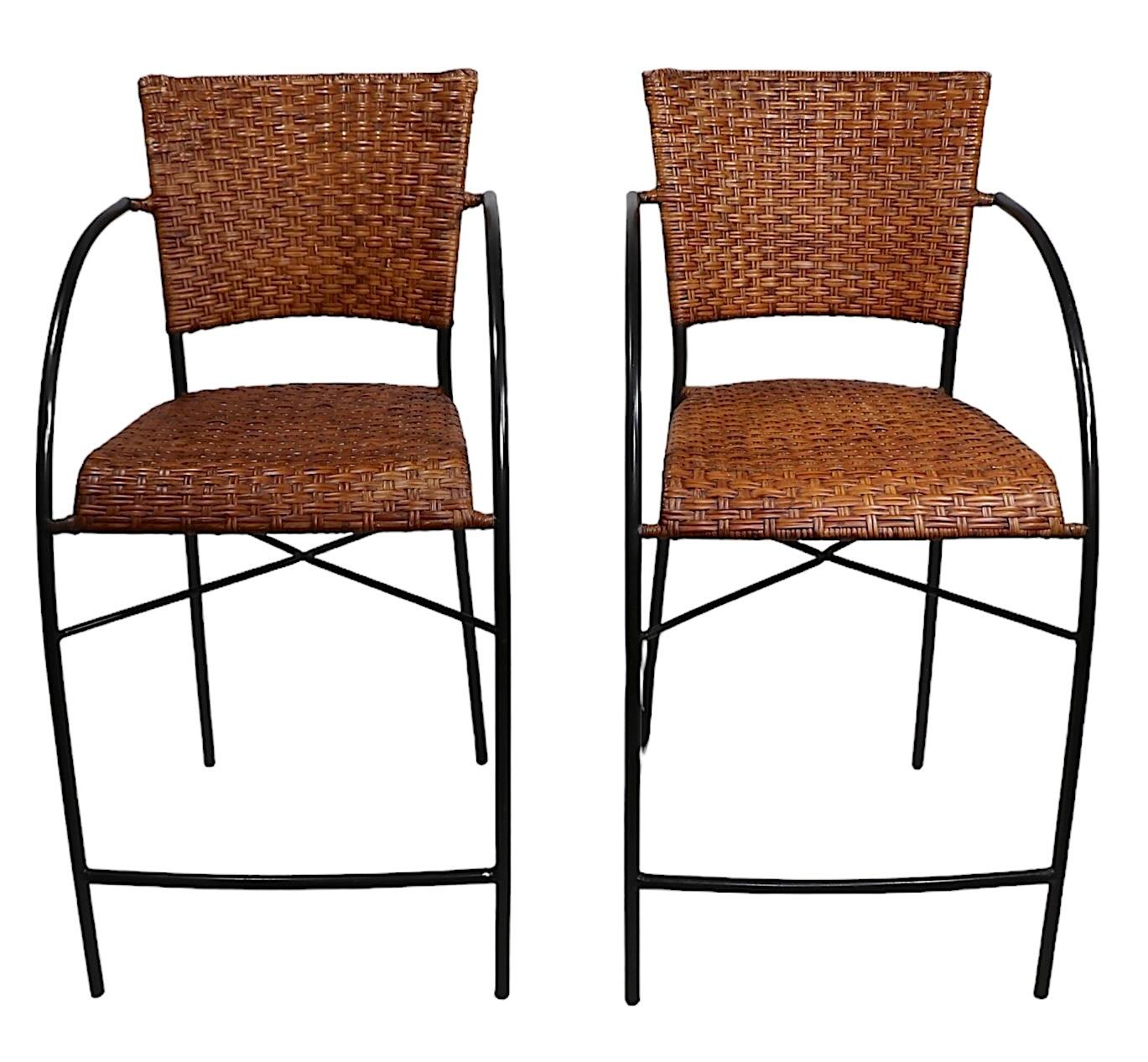 Chic pair of vintage counter height rattan and wrought iron stools, in very fine, original, clean and ready to use condition. Constructed of iron frames with woven rattan seats and backrests. Circa 1960/80's made in the USA.  Design reminiscent of