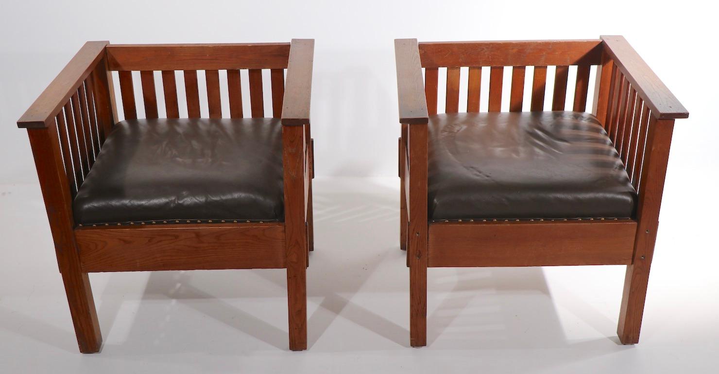Pair of Prairie style Mission cube form lounge chairs, in very good original condition. The even arm frame is of solid oak, the inner spring drop in cushions are in brown leather, with brass studs. In the style of Stickley, Limberts etc, unsigned.