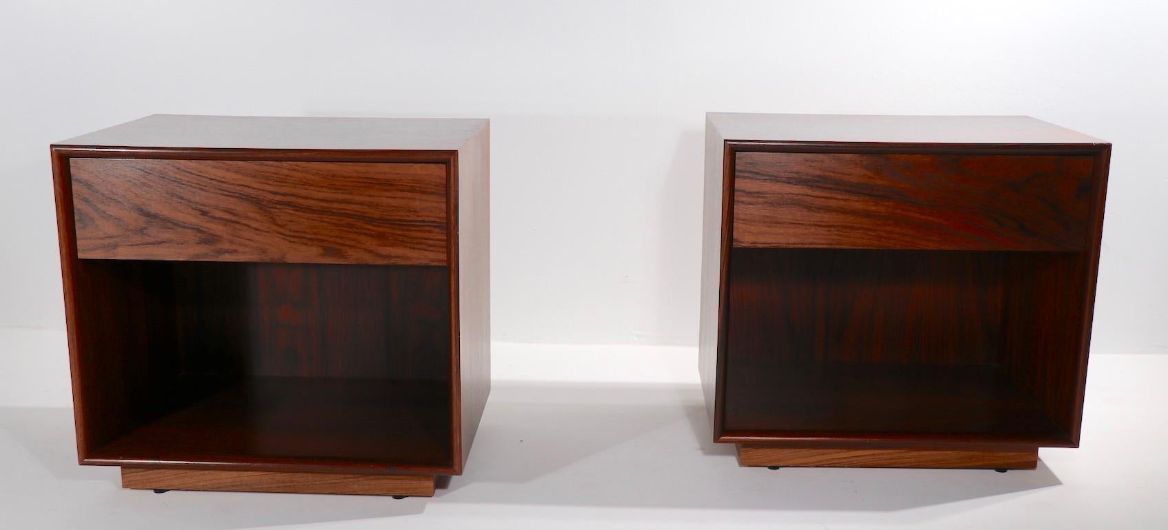 Chic pair of rosewood cube form night tables, having one drawer over open an storage space. Both are in very clean, original condition, ready to use, both are marked Made in Sweden. Drawer interiors are white, one drawer bottom shows slight