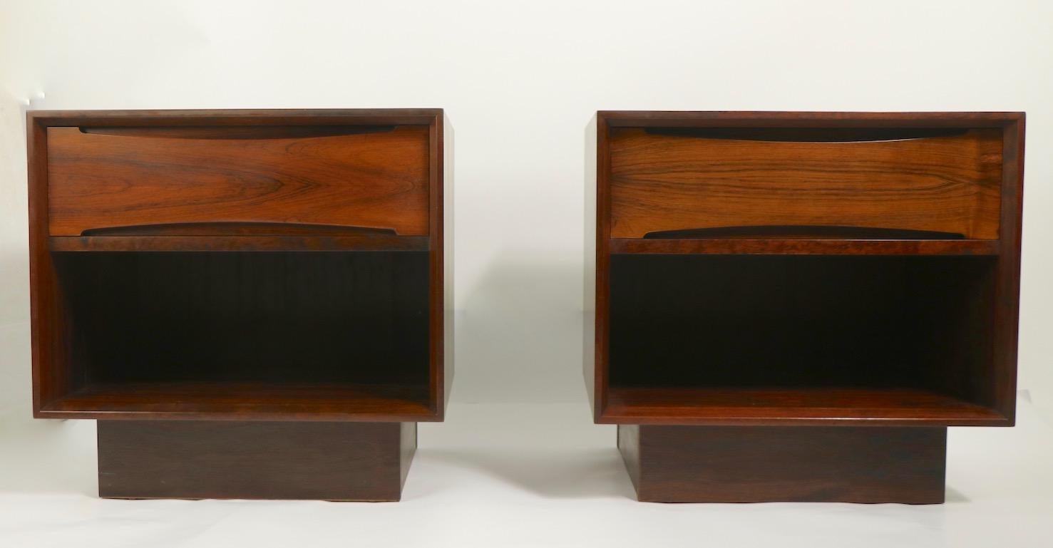 Chic pair of Danish modern night tables in rosewood by Drylund. The night stands are of cube form, having a pull out drawer ( 5.5 inch H ) over an open storage space ( 8 inch H ), on a square plinth base. Both are in very fine, original clean