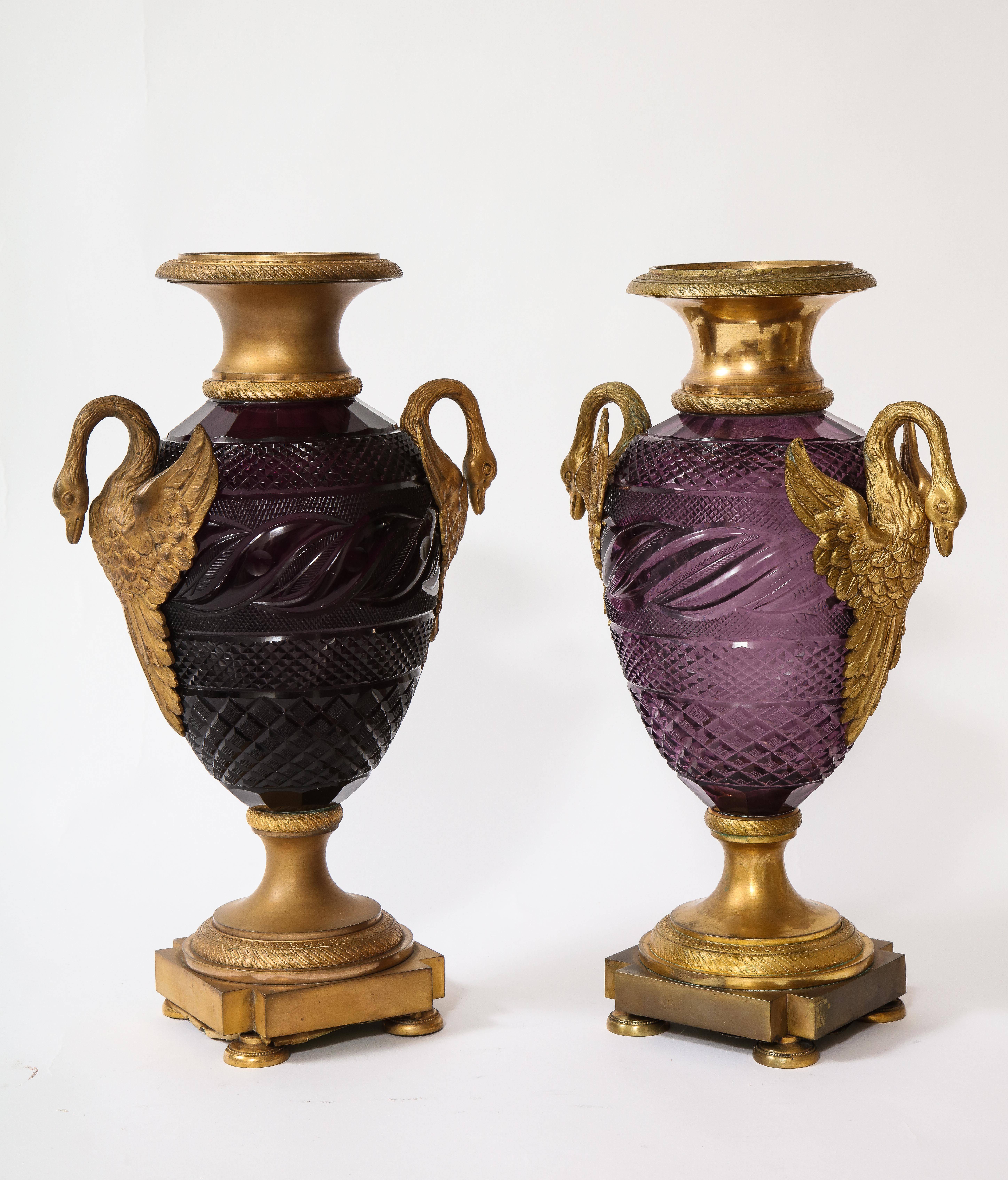 An exquisite pair of Russian Louis XVI style doré bronze mounted hand-diamond cut amethyst crystal double swan handle vases. The doré bronze swan handles are beautifully matted and burnished finished with hand-chiseled and hand-chased details to the