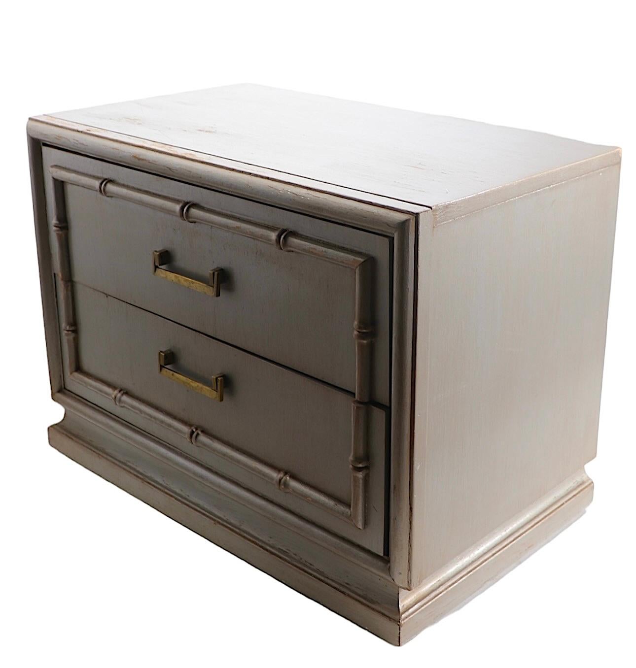 Pair of stylish nightstands, or side, or end tables. Executed  in silver gilt finish with decorative  faux bamboo trim, and brass handles.
The night tables are structurally sound and sturdy, both show cosmetic wear, minor flaws and blemishes, normal