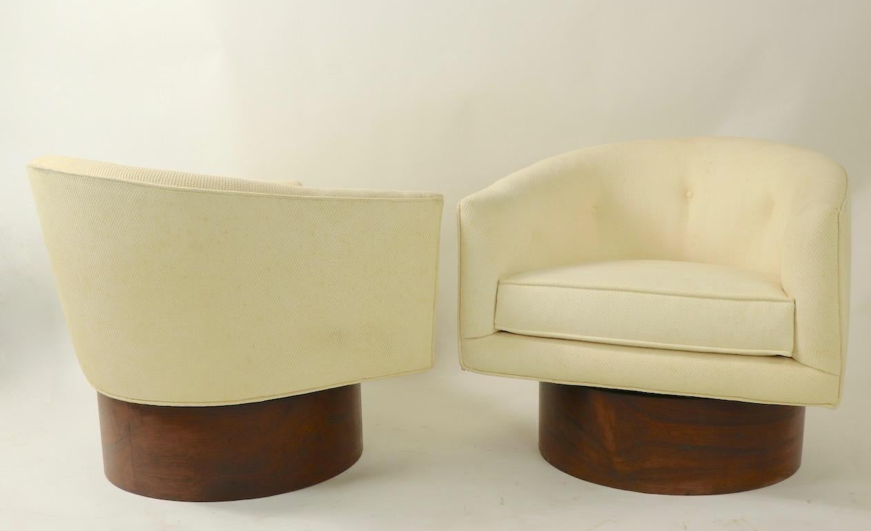 Exquisite pair of swivel chairs designed by Milo Baughman for Thayer Coggin. The upholstered chairs are mounted on exaggerated scale rosewood (veneer) plinth bases. Well crafted and superb design, sophisticated and chic pair of chairs by recognized