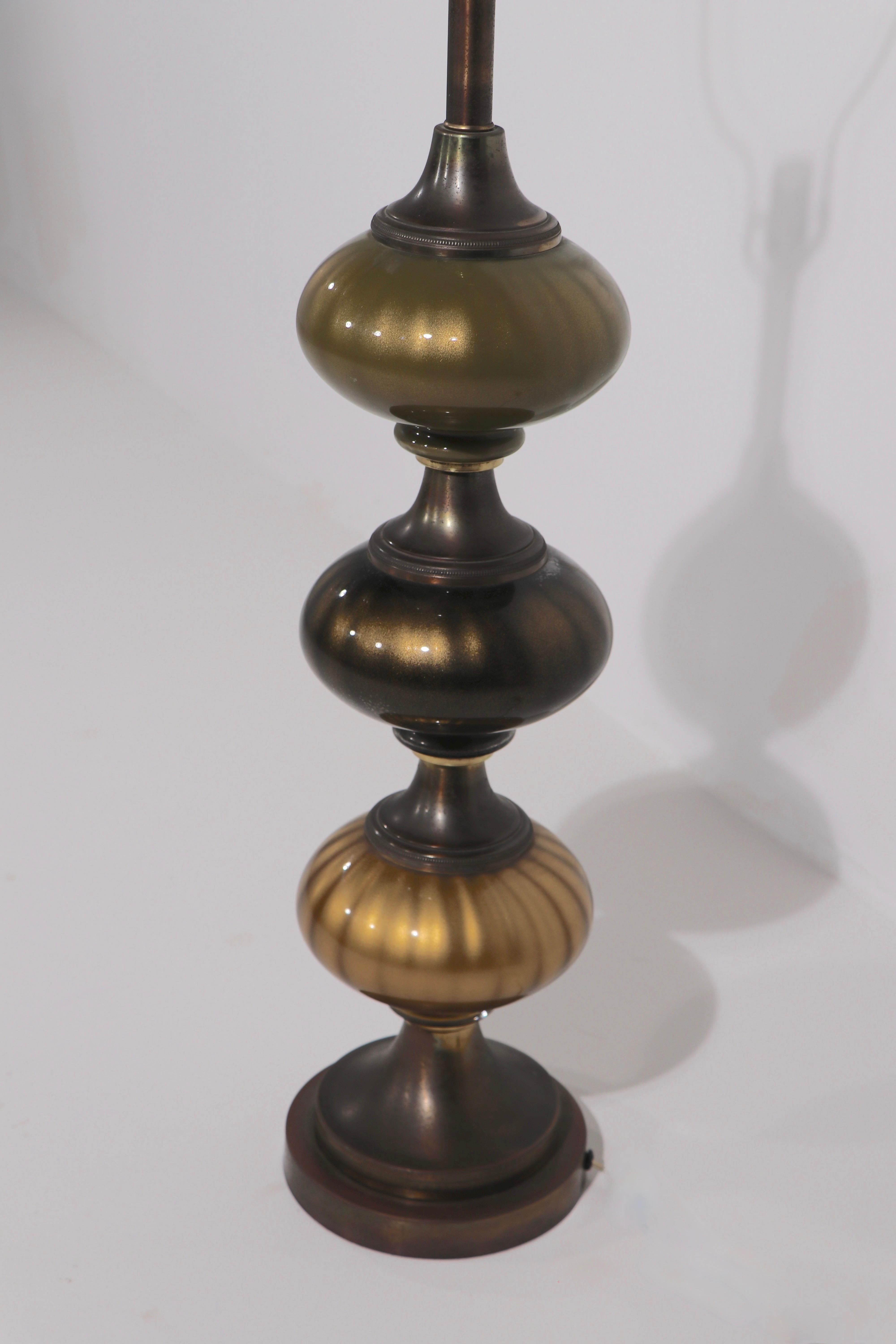 Impressive pair of mid century table lamps, having stacked art glass orbs, in three tones, brown, green, and gold , all with gold fleck inclusion. In the Italian style, probably American made, circa 1950/1960 vintage.
Both lamps are in very good,