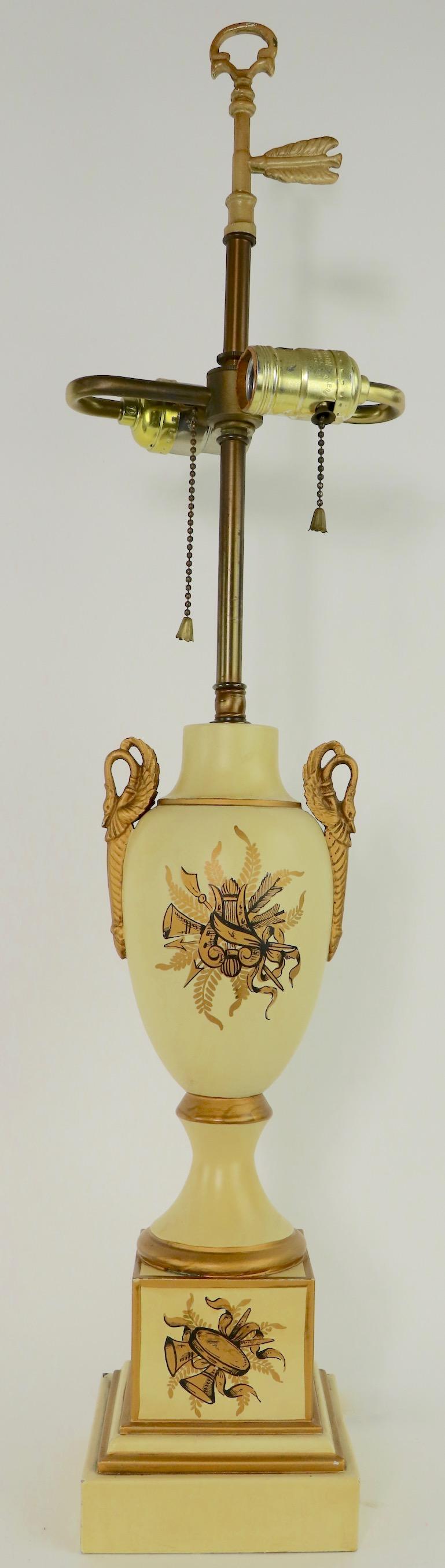 Classical urn form tole decorated table lamps, having bases made in France, for the Tyndale Lamp Company. Each lamp has bird form handles, on pale yellow bodies, with stepped plinth bases. In the 18th century French Empire style, circa 1960s-1970s.