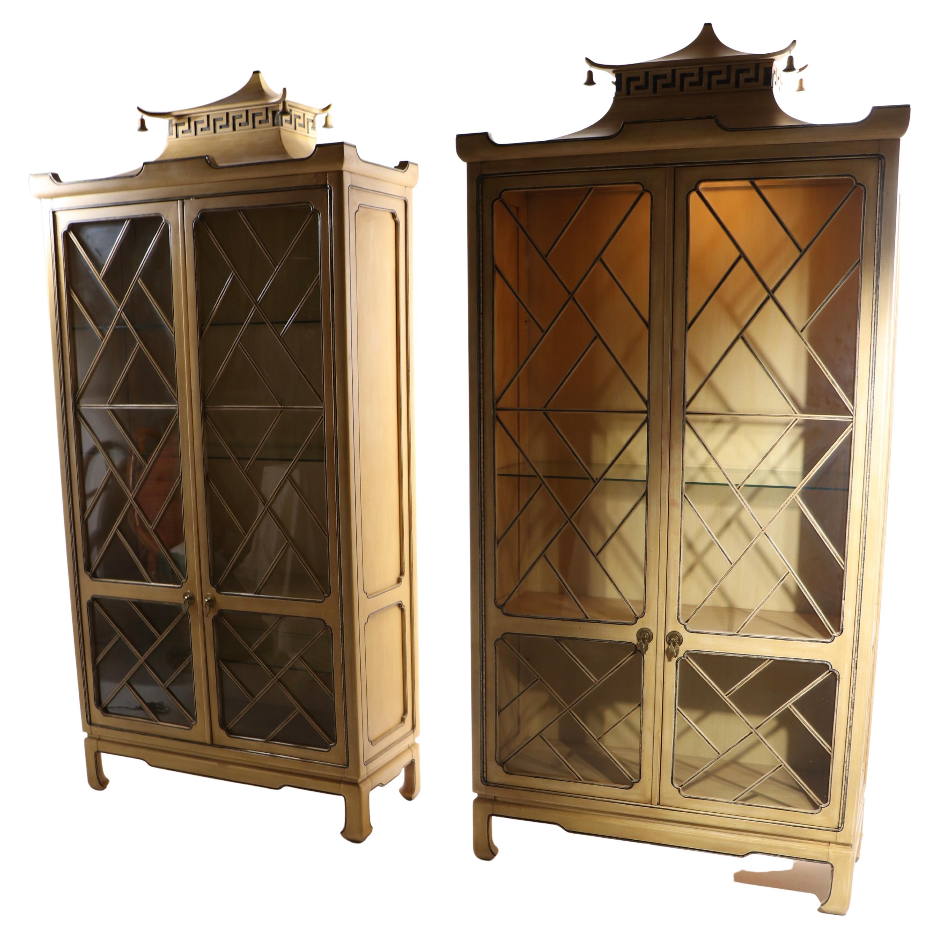 Incredible pair of Tomlinson Pagoda vitrines, in the Chinese Chippendale, Hollywood Regency style. Each cabinet has two swing out door which open to reveal a fixed wood shelf, and adjustable glass shelves, and an interior light at the top. The cases