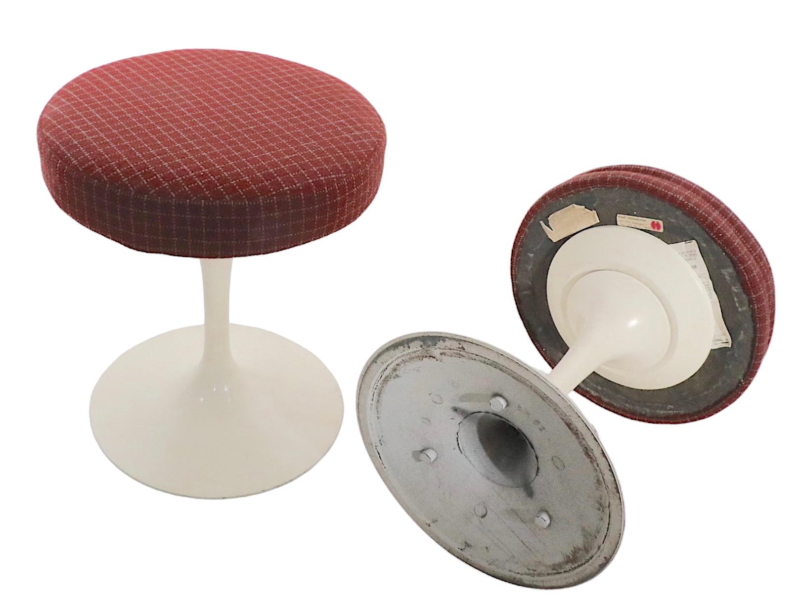 Classic Tulip stools, designed by Eero Saarinen for Knoll. These iconic stools are in good, original condition, the upholstered tops show some wear, they are usable as is, or we offer custom upholstery if you prefer a more polished look. Both retain