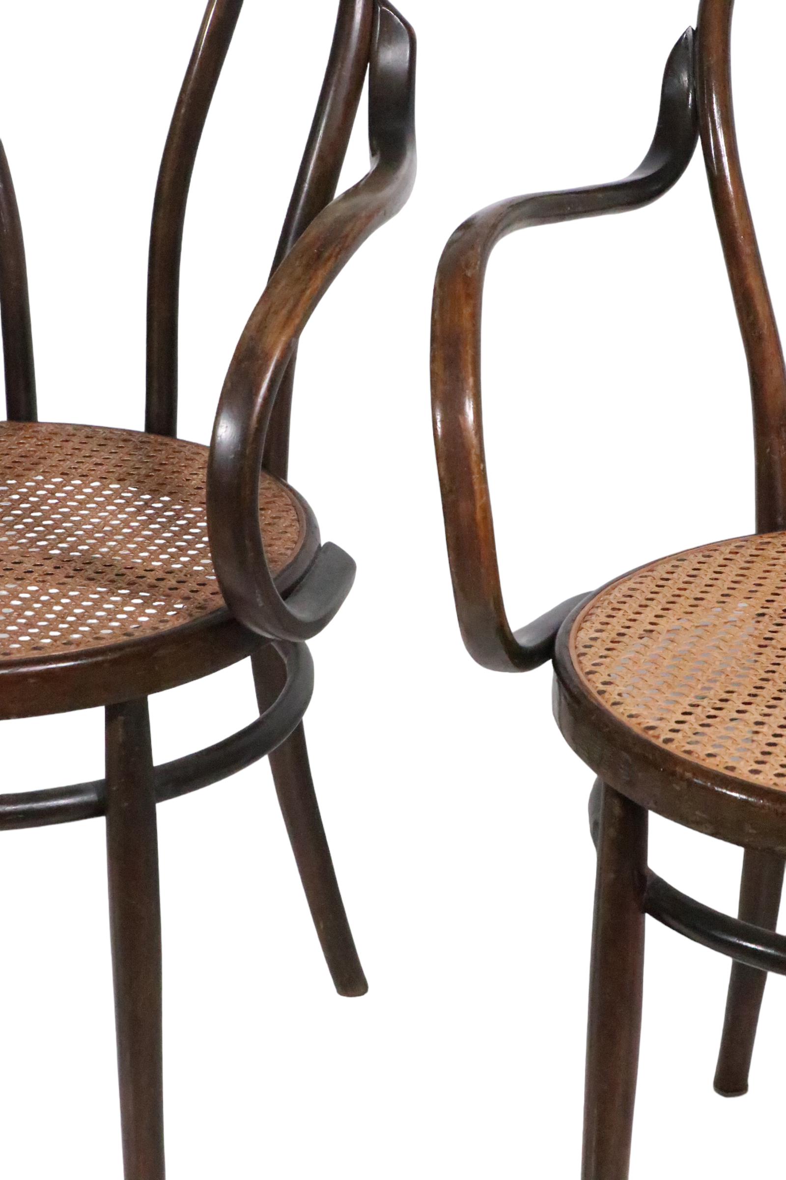 Chic pair of Vienesse Secessionist period bentwood arm chairs attributed to Thonet. The chairs are constructed of steam bent beech wood , and cane. These fine chairs are classic examples of the early roots of the modern design movement, circa 1880/