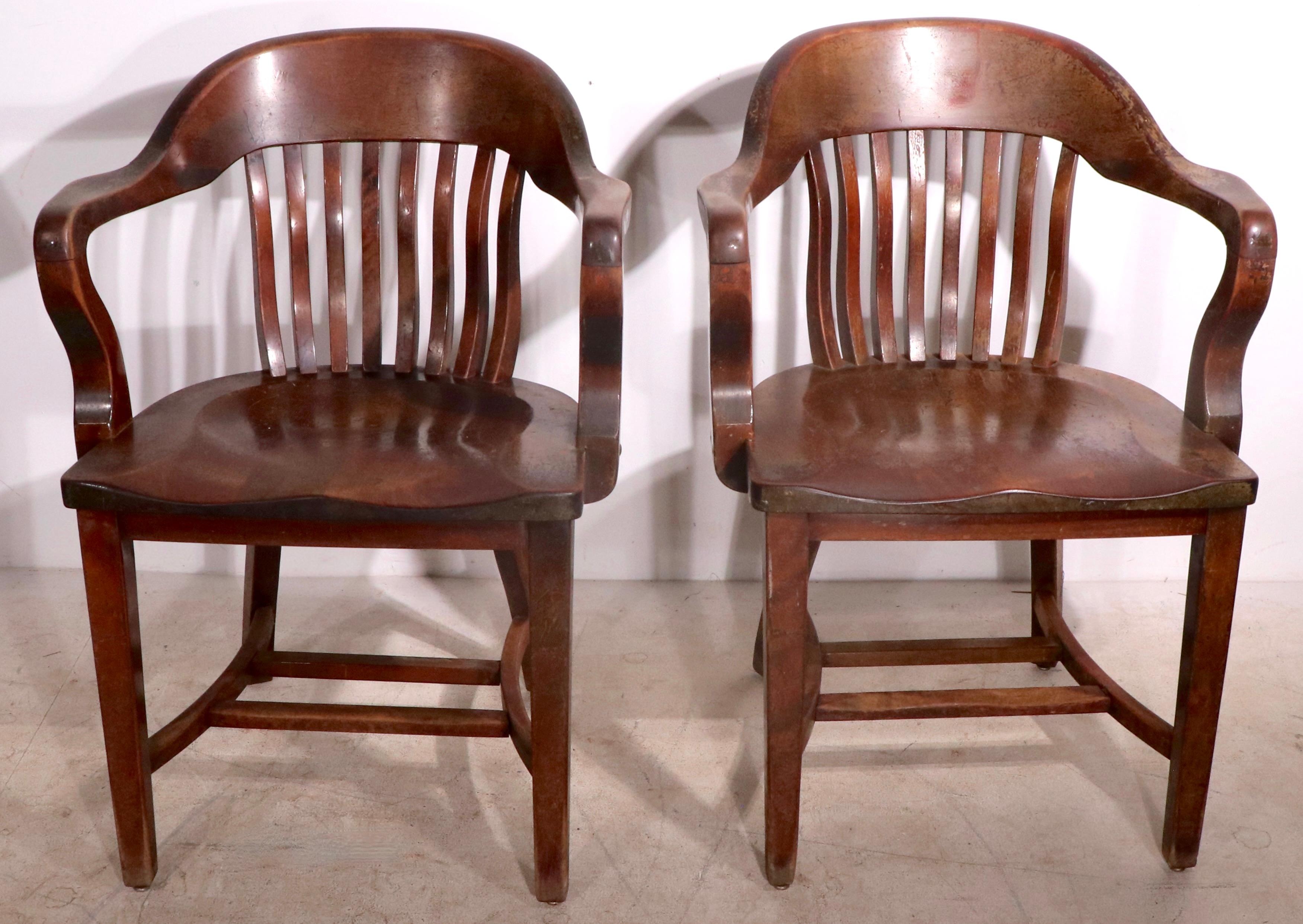 Pair of classic Bank of England, Yale Library, Jury chairs, in solid walnut, in mahogany finish. The chairs are structurally sound, both show cosmetic wear to finish, please see images. Priced and offered as a pair.
 Measures: total H 33 x arm H