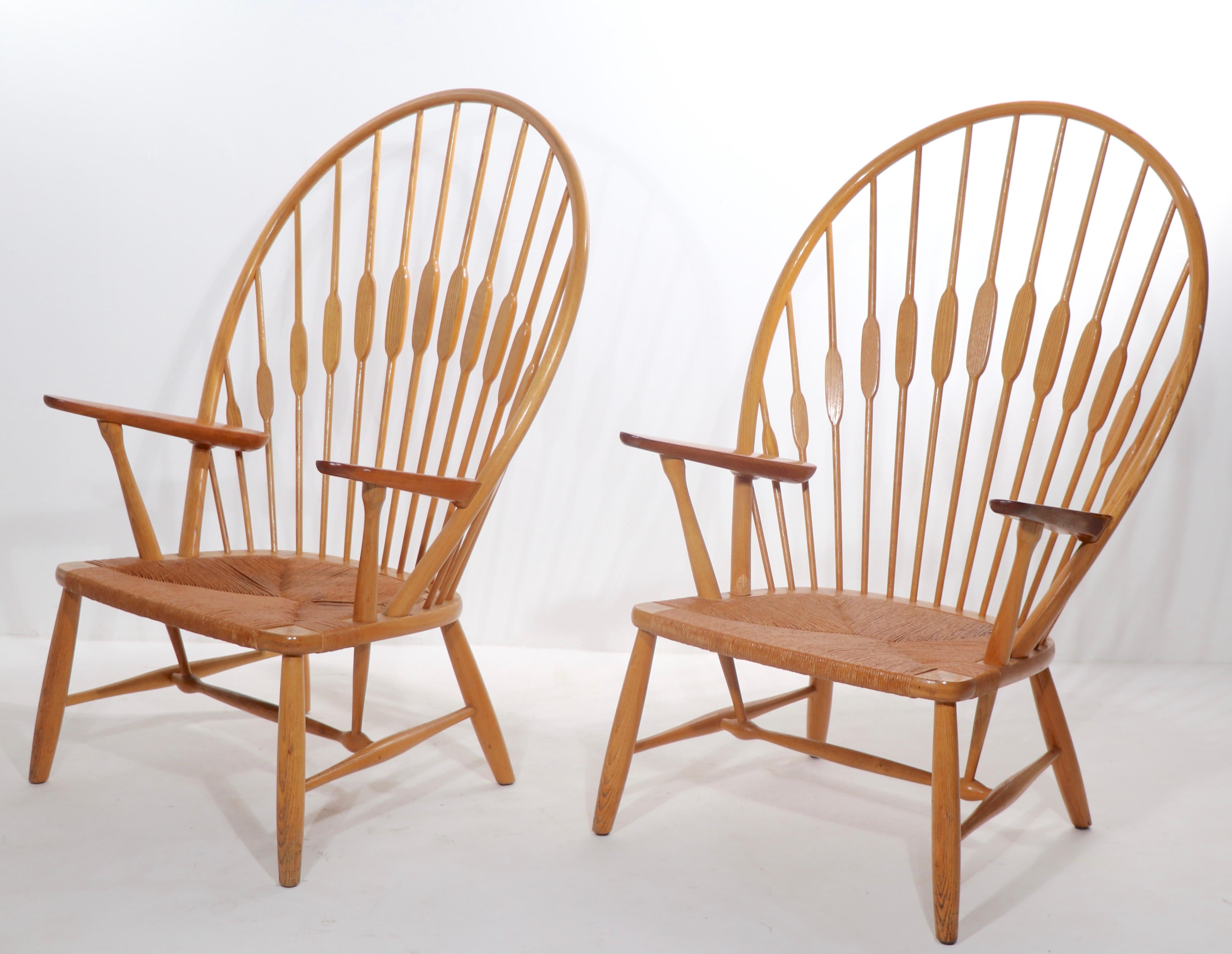 Coppia iconica di capolavori della modernità danese, le Peacock Chairs, disegnate da Has Wegner e realizzate da Johannes Hansen, Copenaghen Danimarca, circa anni '60. Costruita in frassino e teak, con sedute originali in papercoard. Entrambe le