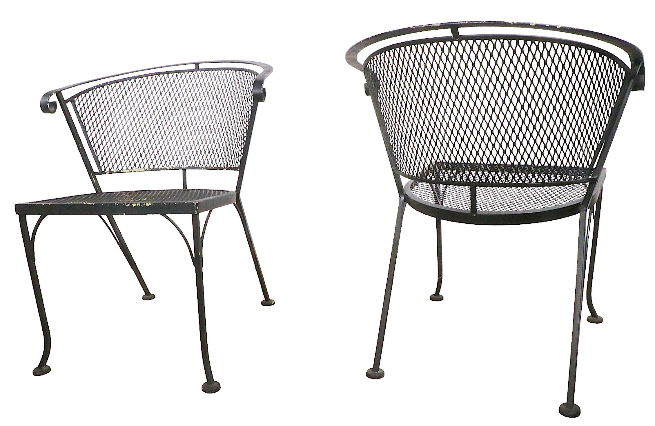 Pair of vintage Garden, Patio, Poolside armchairs attributed to Salterini. The chairs feature metal mesh seats and backs, with wrought iron frames. Both are in good original condition, showing only light cosmetic wear, normal and consistent with