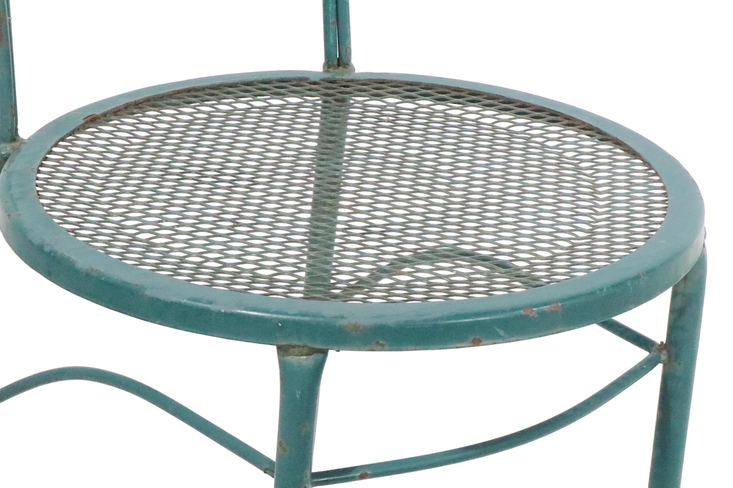 Super chic and voguish pair of wrought iron, metal, and metal mesh garden, patio, or poolside dining height chairs. The chairs feature a curved  tubular backrest , wrought iron frame, and metal mesh seats. Both chairs are structurally sound and