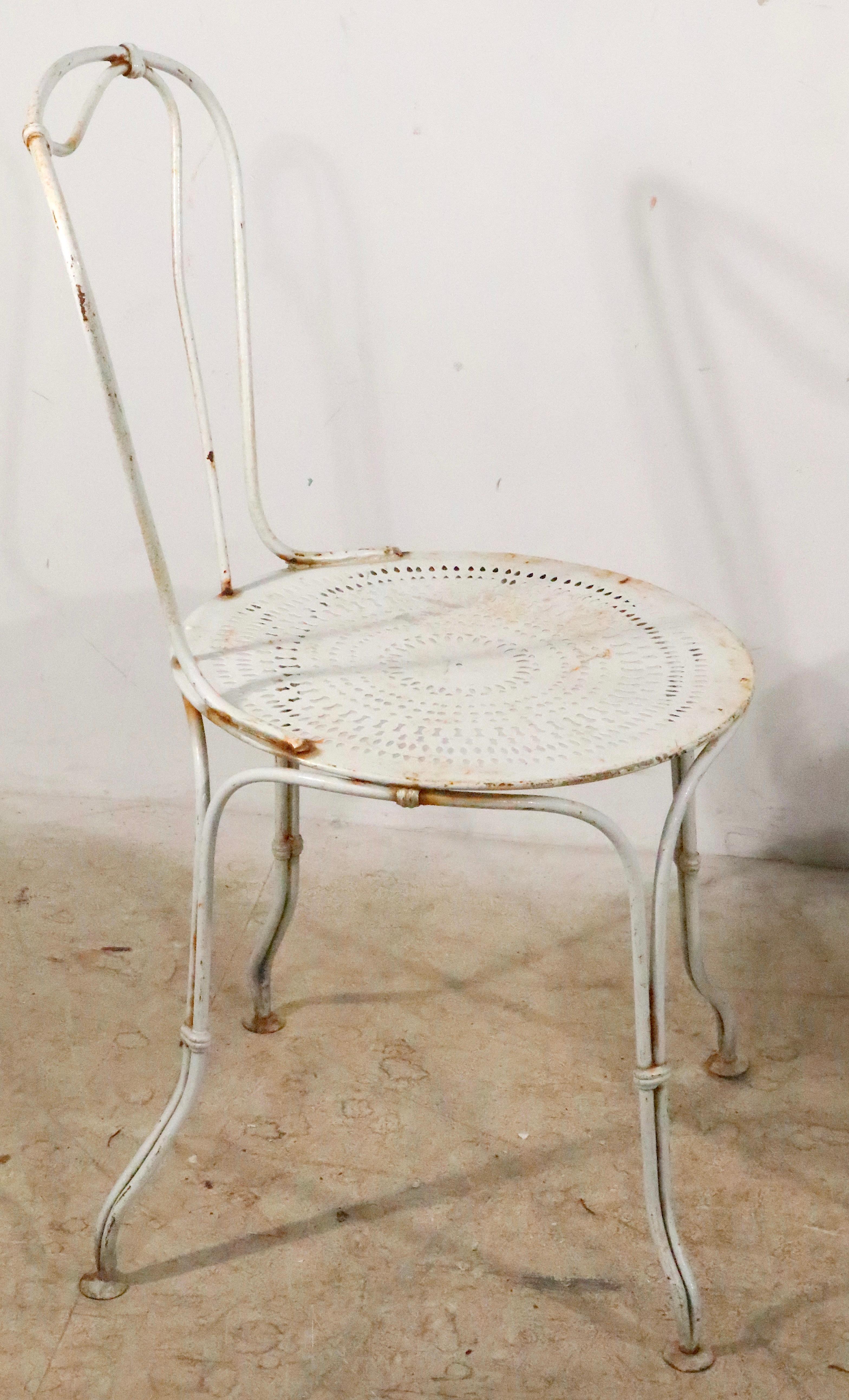 Pair of charming wrought iron and steel cafe, bistro, garden patio chairs made in France, circa 1930- 1950s. Both chairs are in very good, original condition, structurally sound and sturdy, showing only the expected cosmetic wear to the paint