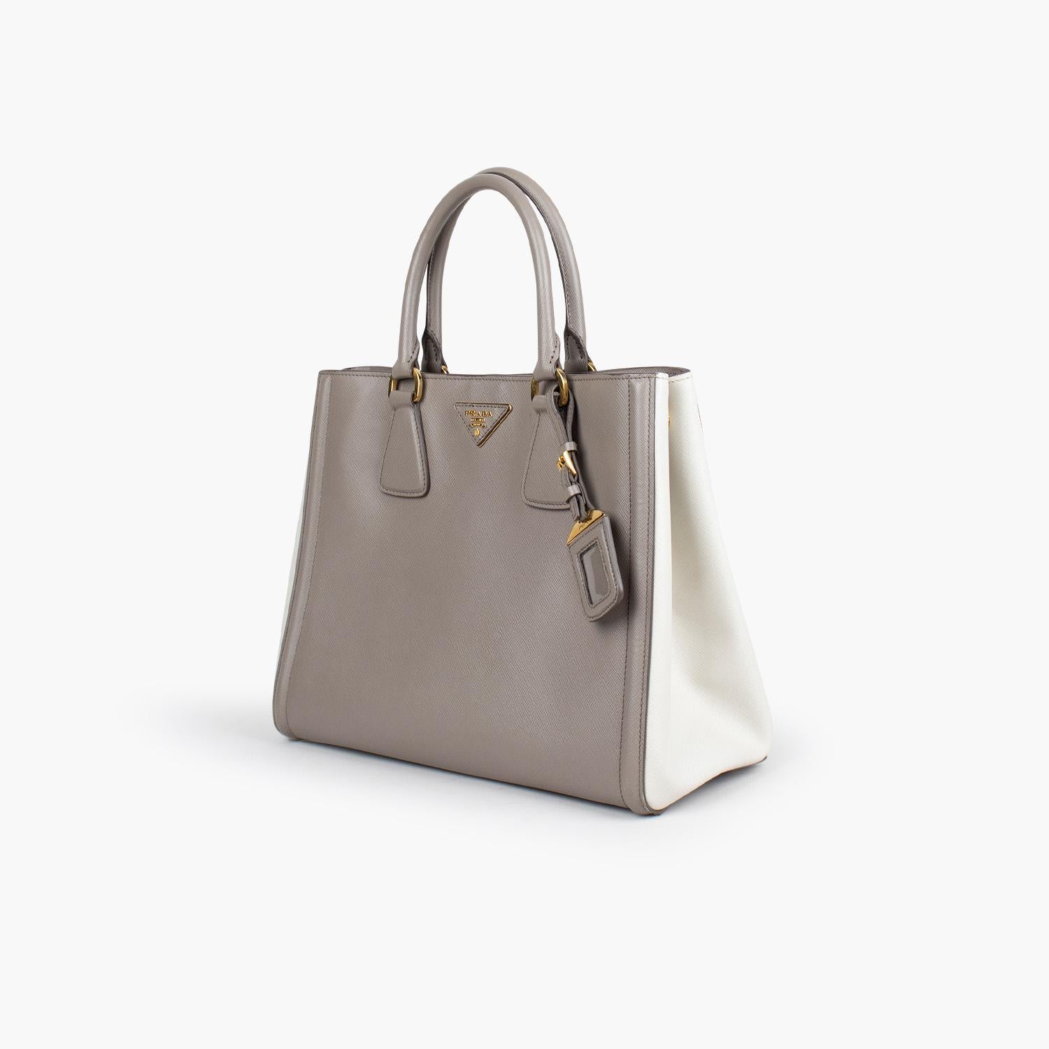 Grey and Cream Bicolor Saffiano Lux leather Prada tote with

- Brass hardware
- Dual rolled top handles
- Single detachable flat adjustable shoulder strap
- Logo placard at face
- Protective feet at base, tonal logo jacquard lining, five interior